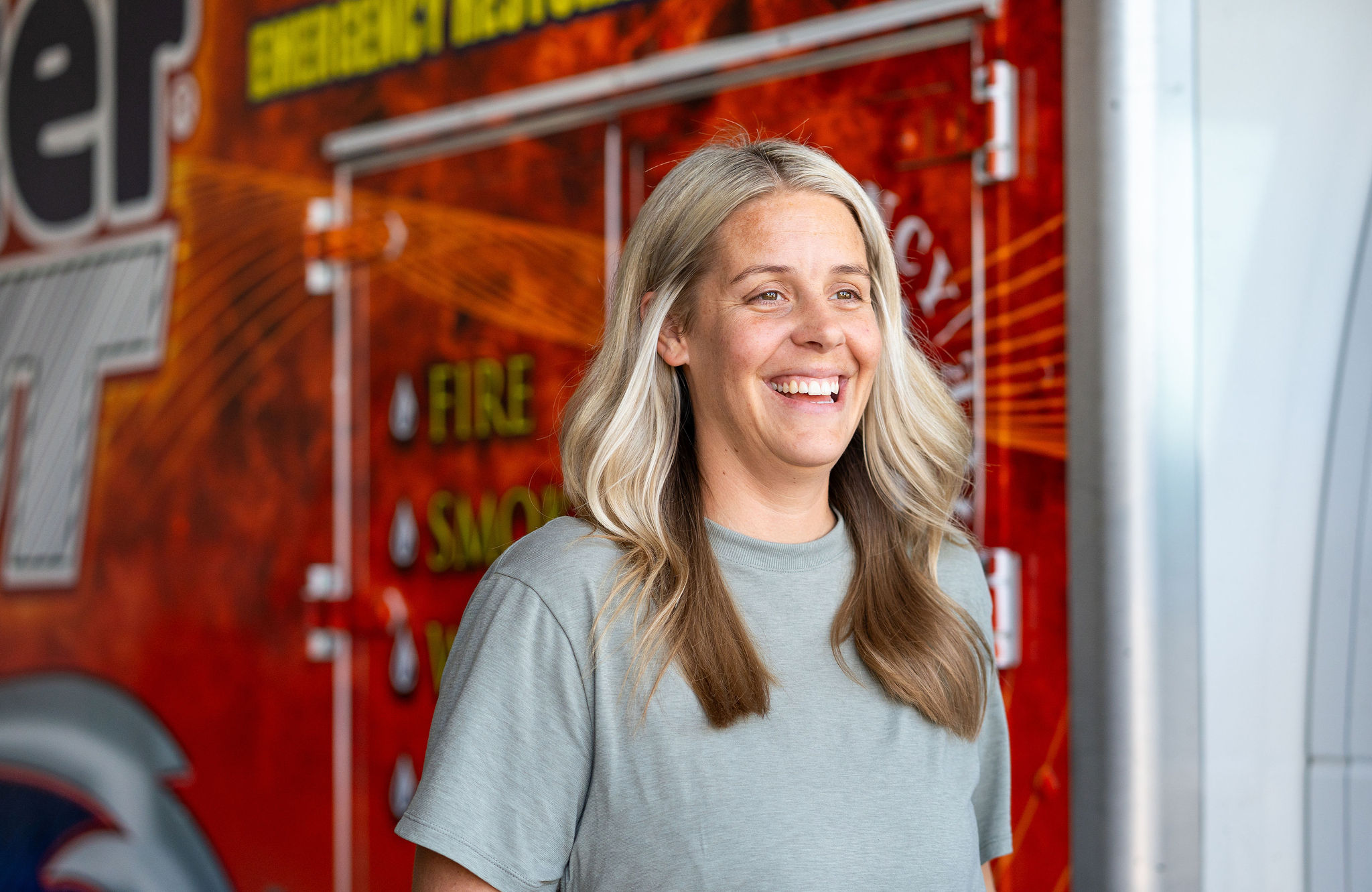 A person laughs and smiles in front of a red work truck.