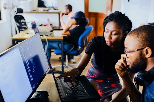 Two students collaborating on coding at a laptop computer