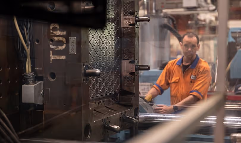 a plastic manufacturing staff member operating a plastic injection moulding machine