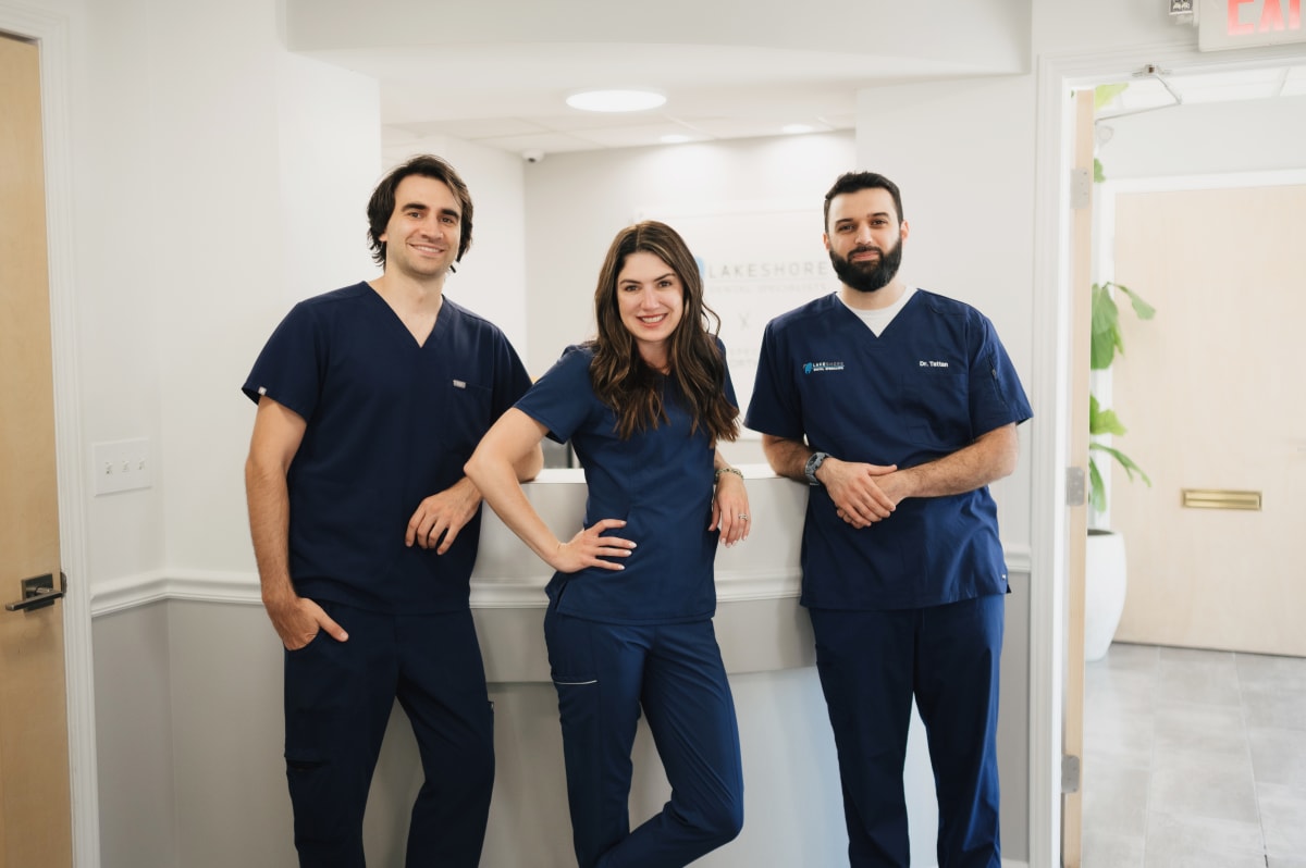 Dental team members in blue scrubs standing together in a modern office hallway