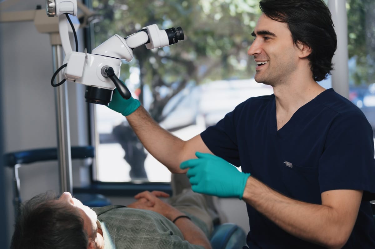 Dentist in dark scrubs performing an implant procedure with specialized surgical instruments