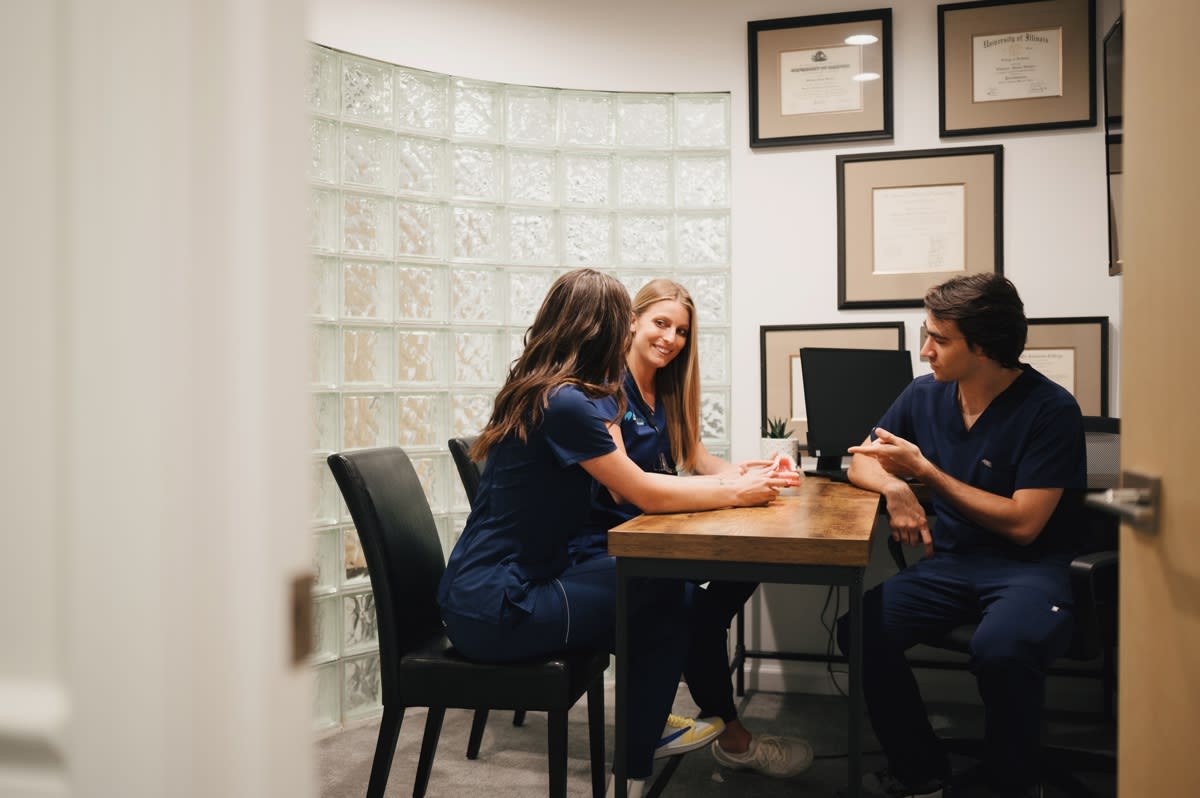 Female dentist consulting with patient at desk in modern dental office