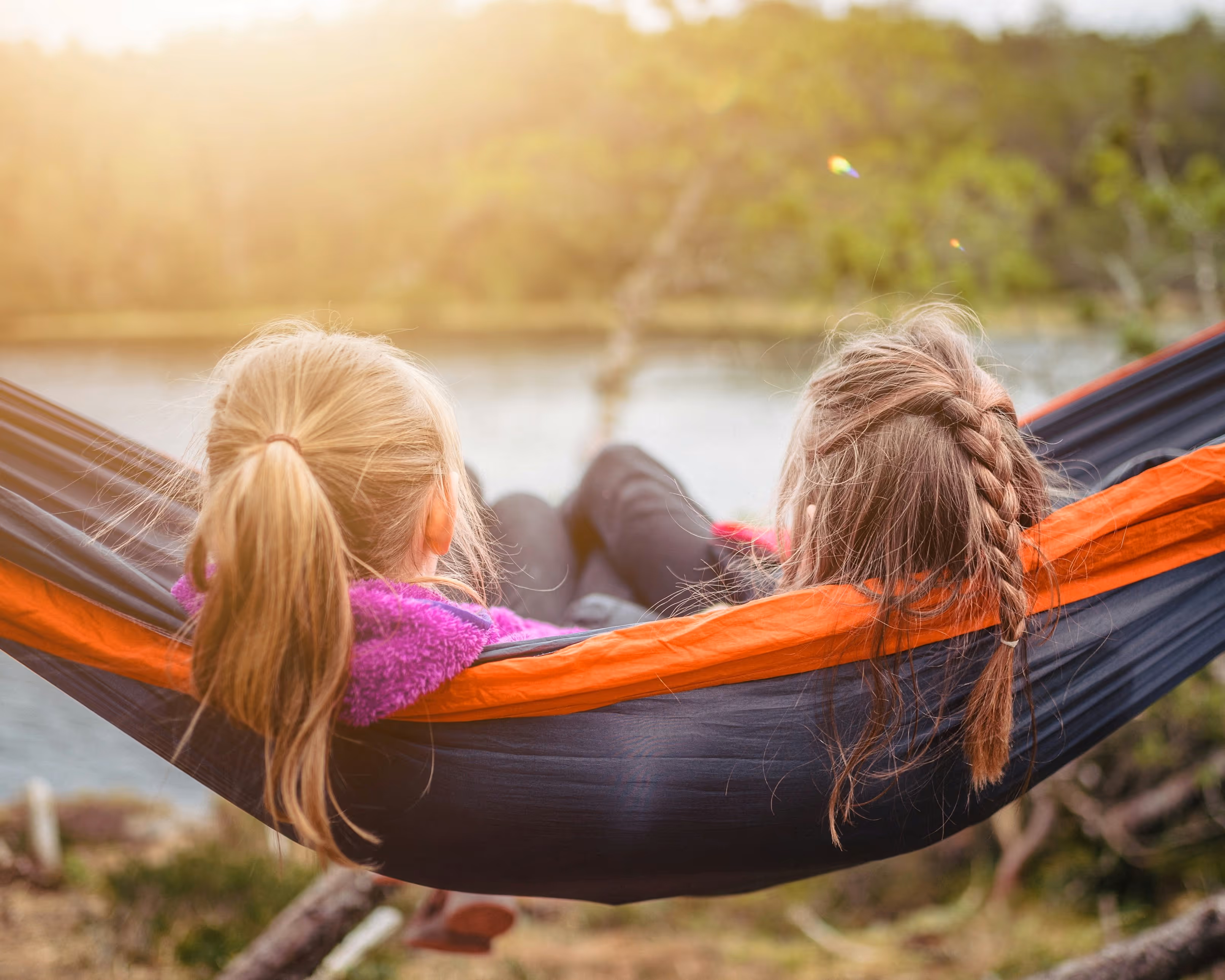 two young girls in a hammock overlook a river