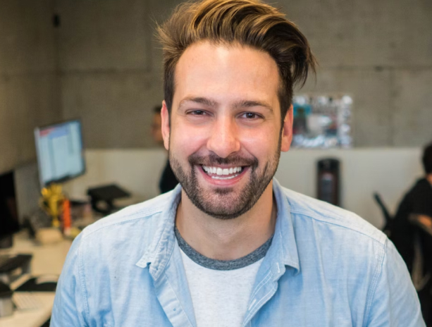 A man with a beard and long hair is smiling.