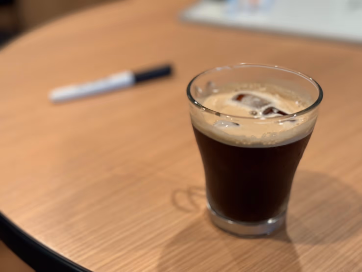 A cup of coffee and a pen on a table.