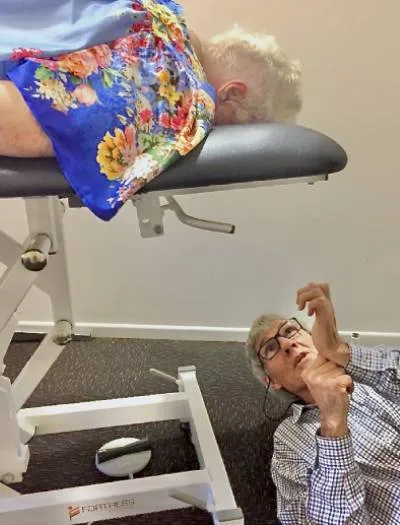 Dr. Gawie Roux lying on the floor while talking to his patient