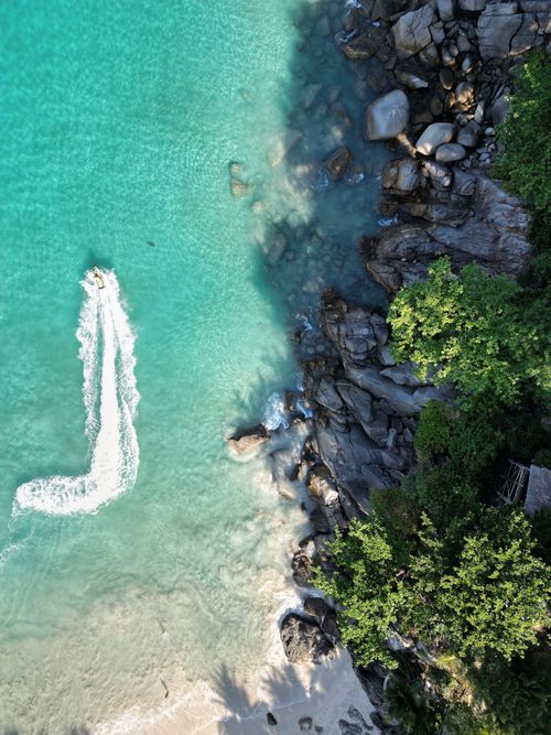 An aerial view of a beach with a boat in the water.