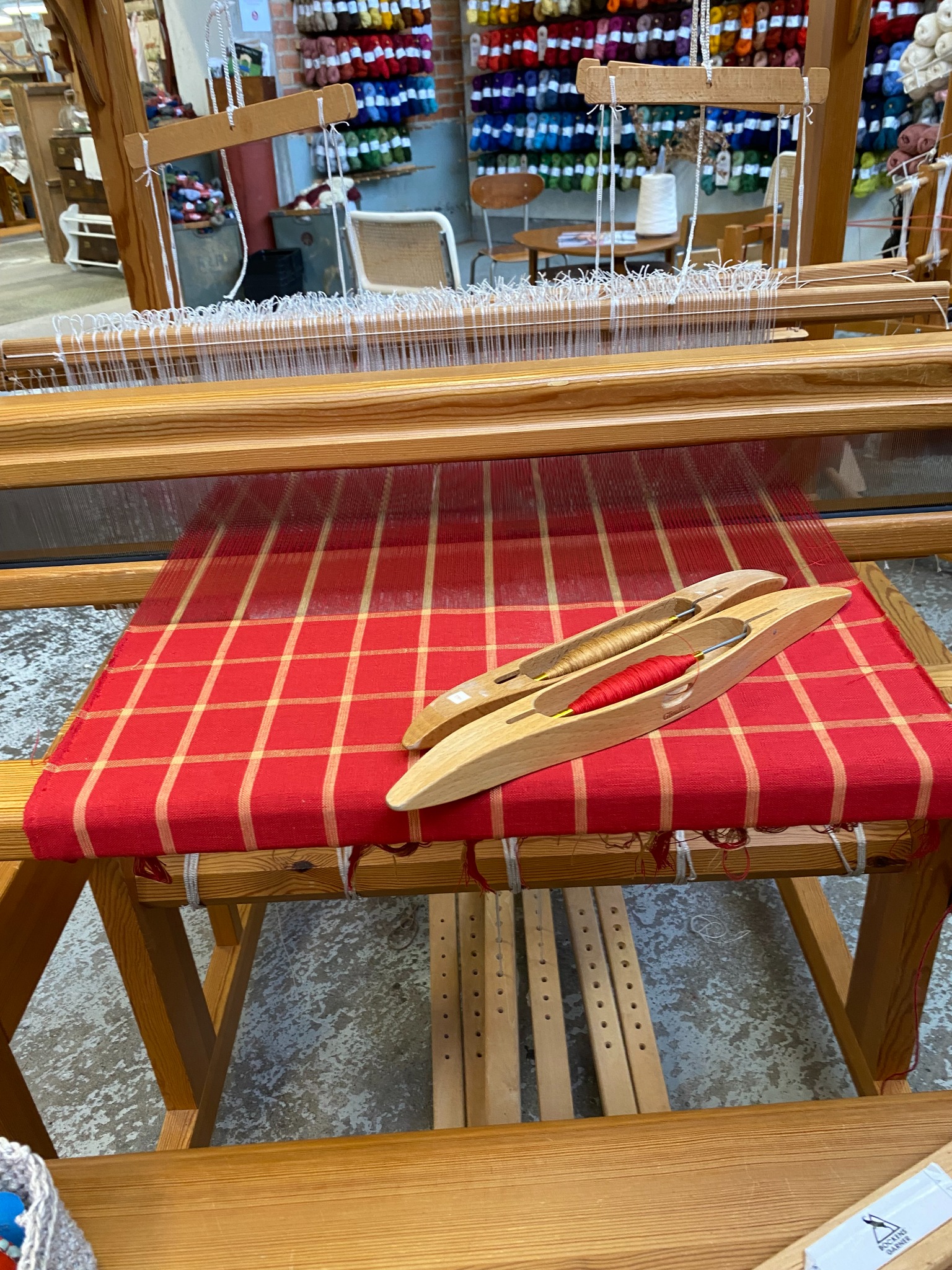 Röda julhanddukar med gyllene rutor vävs i en trävävstol hos Holma.