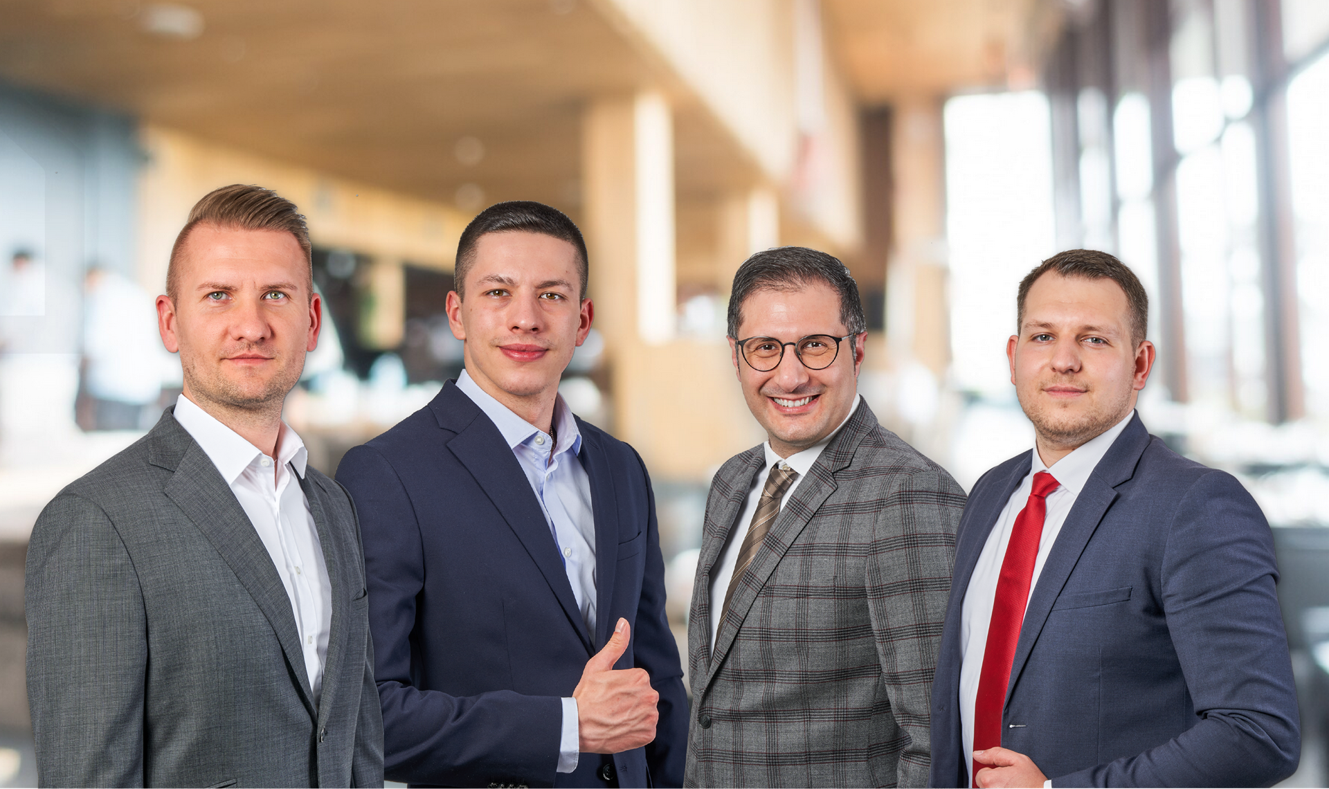 Teambild der Immobilienmakler von Wohnkraft Immobilien im Anzug mit verschwommenen Büro-Hintergrund