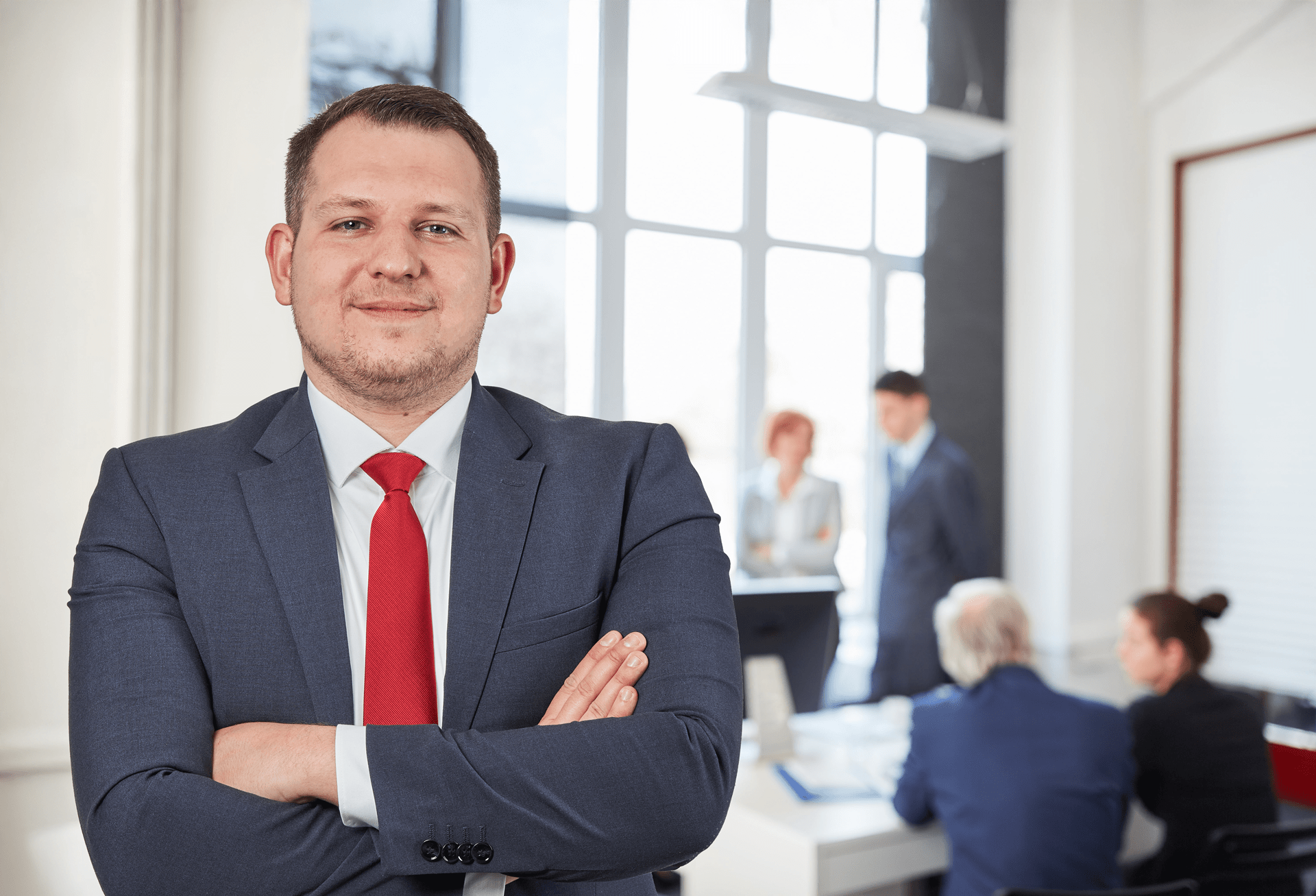 Immobilienmakler im Anzug und Kravatte vor den Mitarbeitern im Hintergrund