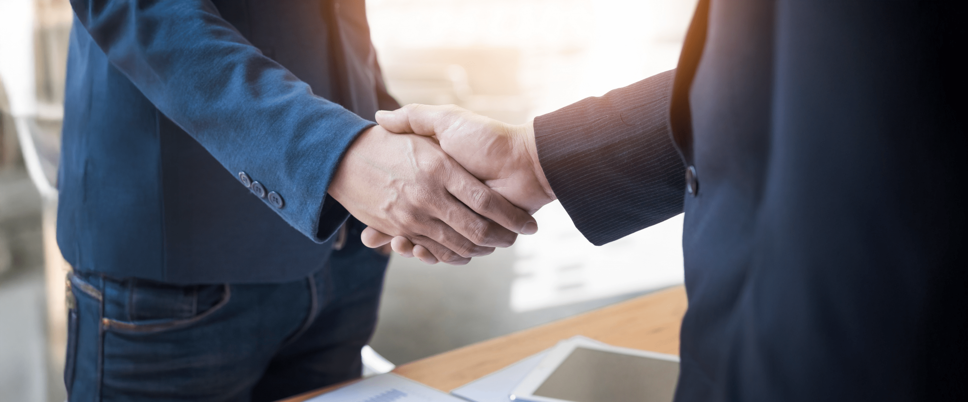 Handshake Bild mit Fokus auf die Hände der Makler im Anzug