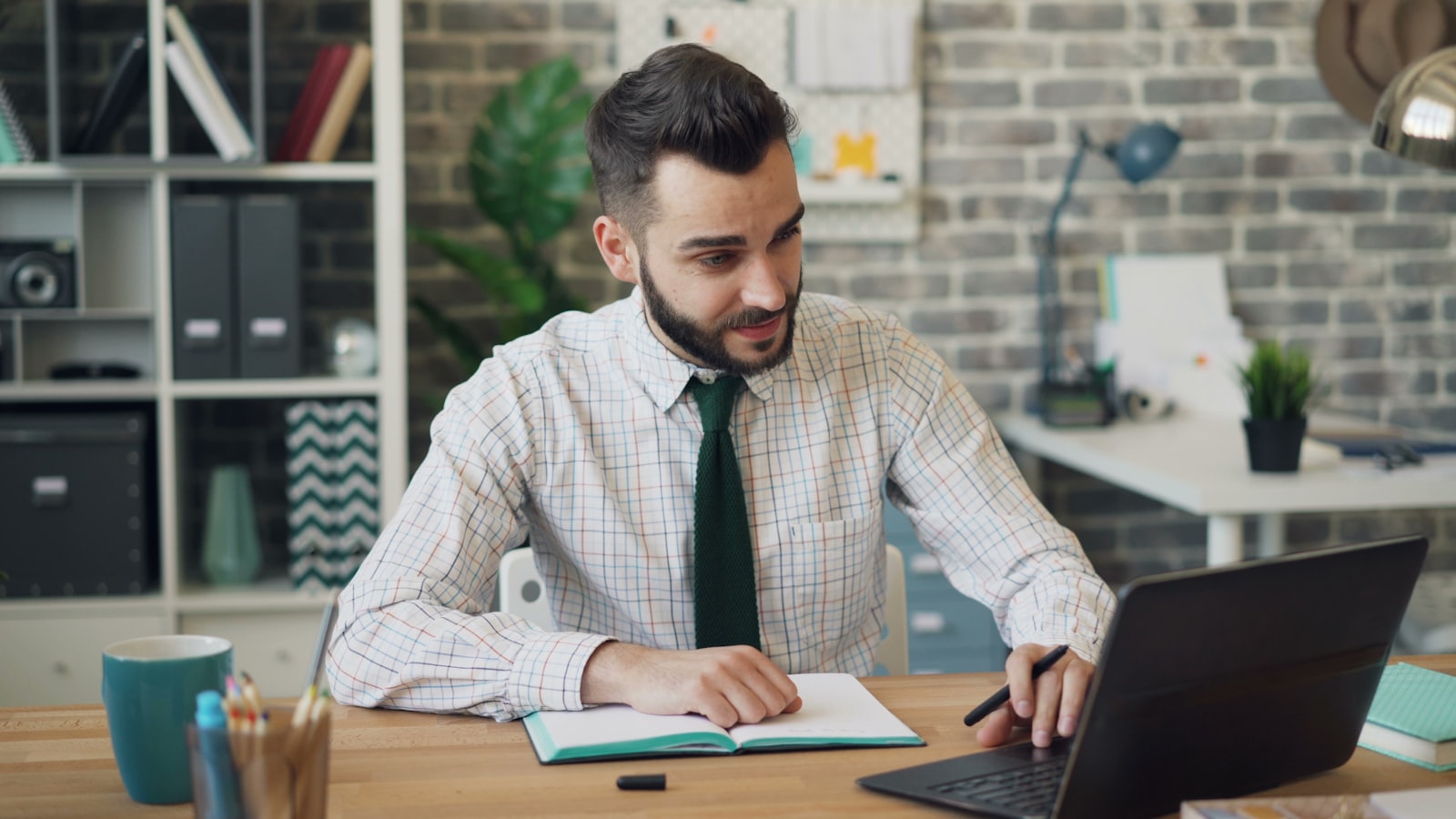 Professional working on a laptop and taking notes at a desk