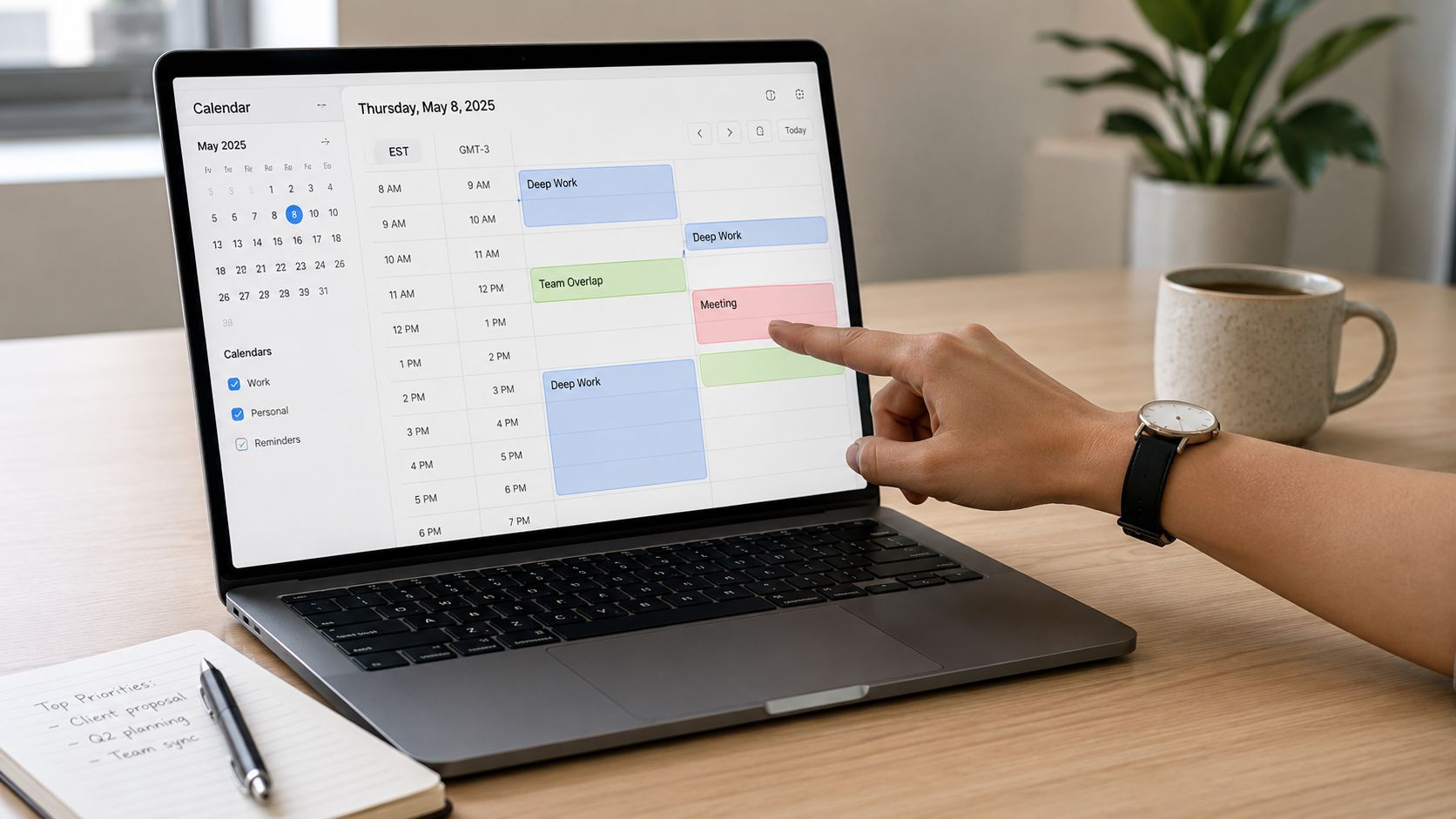 A person using a laptop to view their daily digital calendar schedule on a wooden desk.