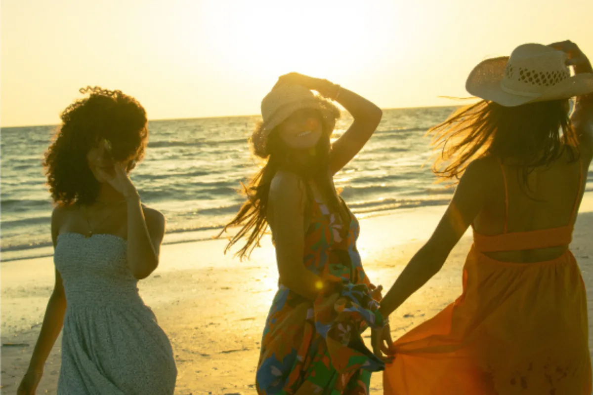 Three friends walking on the beach at sunset