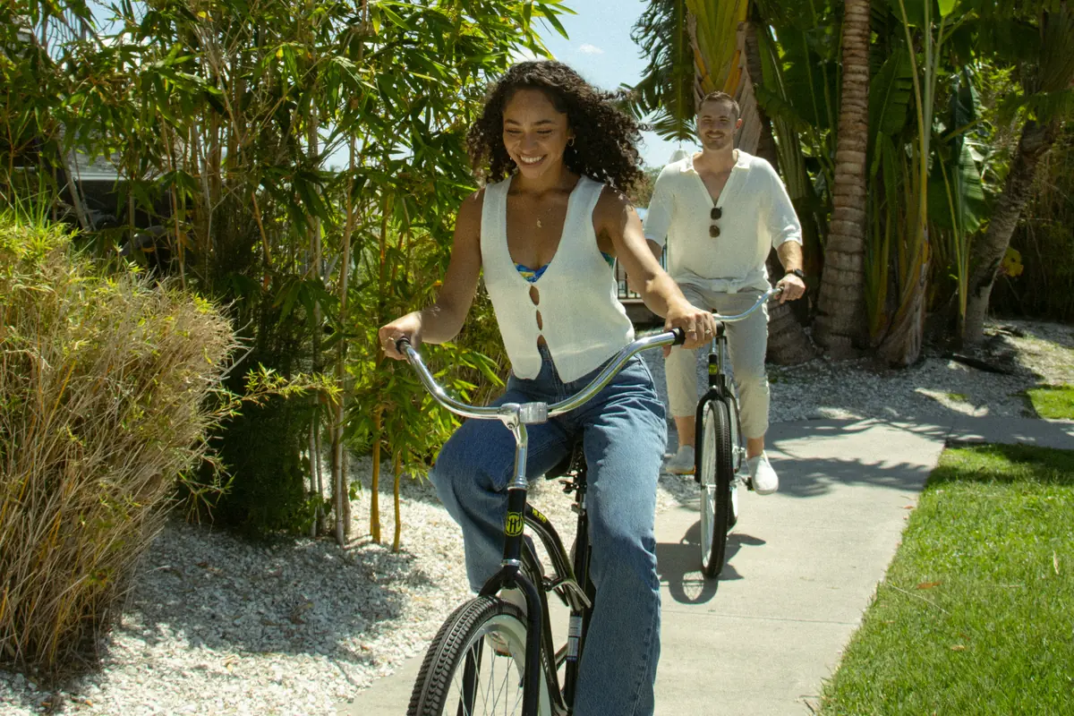 Couple riding bicycles along a palm-lined path