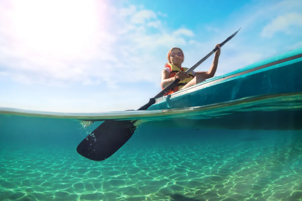 Person paddling a kayak through clear turquoise water