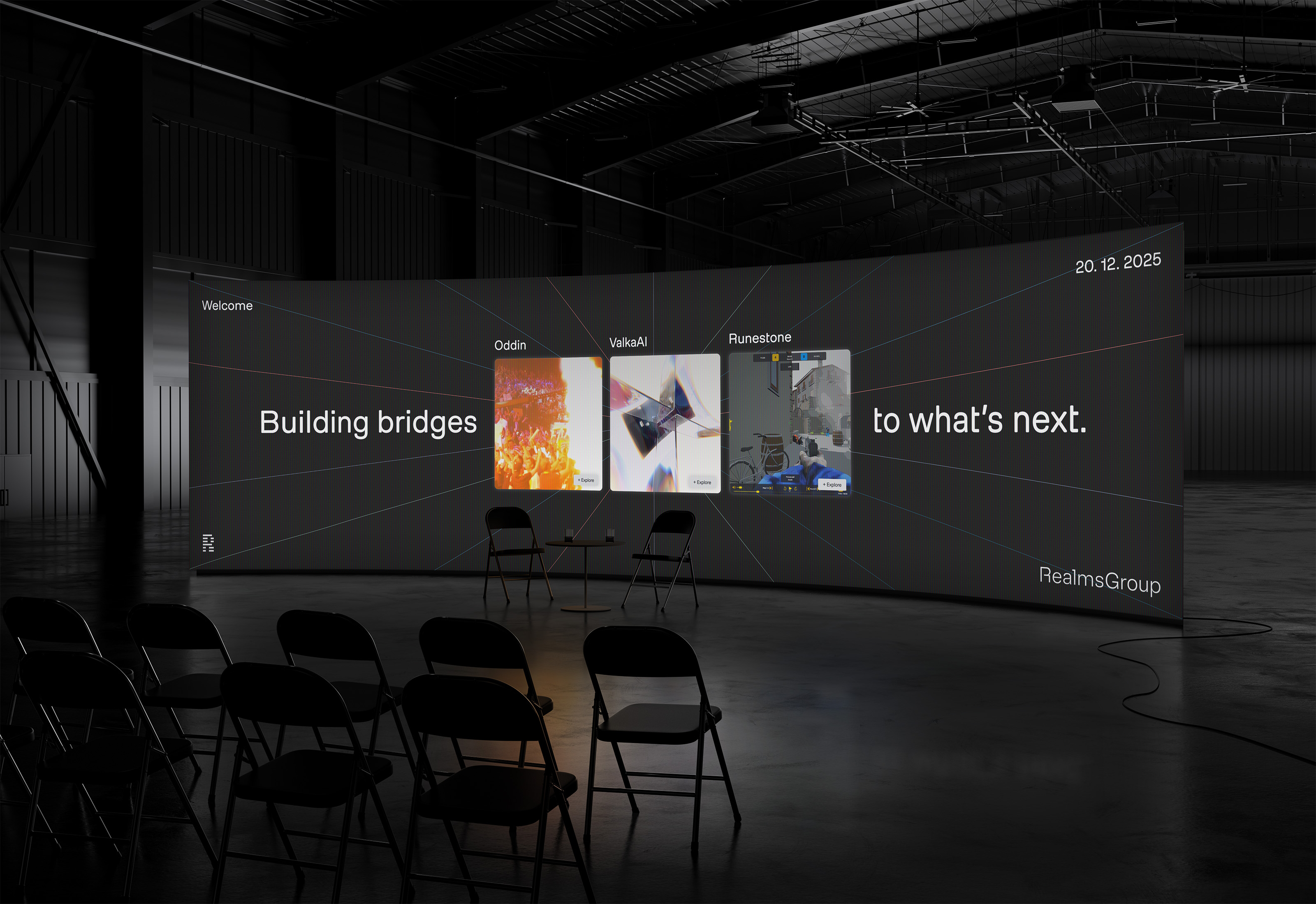 Dark warehouse with a large curved screen displaying 'Building bridges to what's next' and three project cards labeled Oddin, ValkaAI, and Runestone; folding chairs and a small table are in front.