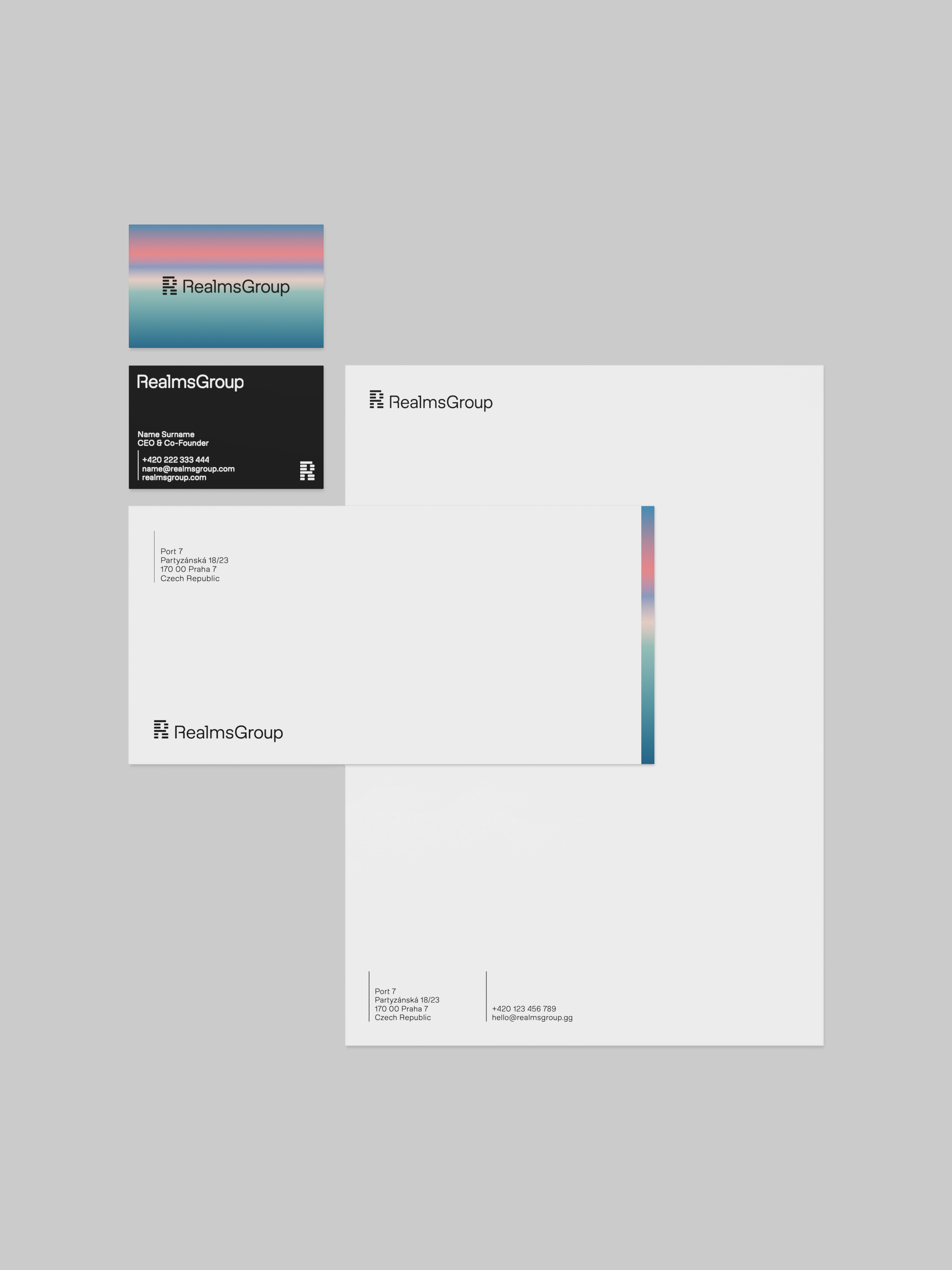 RealmsGroup branded stationery set with business card, envelope, and letterhead featuring a gradient stripe and contact details.
