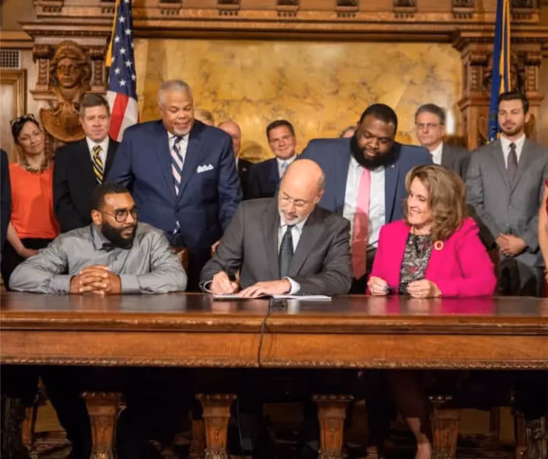 A group of people are sitting at a table signing a document.