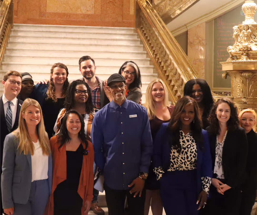 A group of people posing for a picture in front of a staircase.