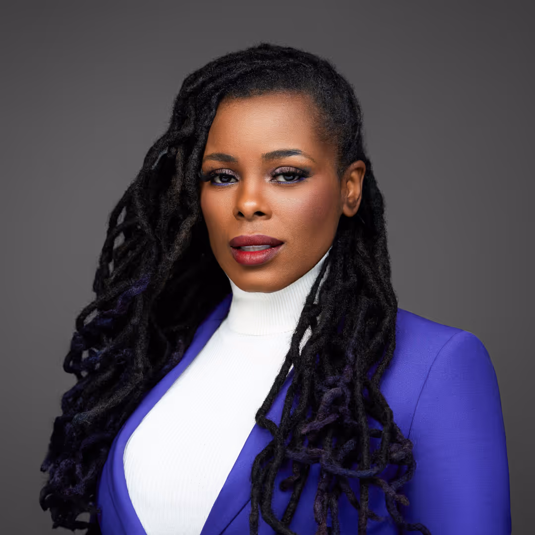 A woman with dreadlocks wearing a purple jacket.