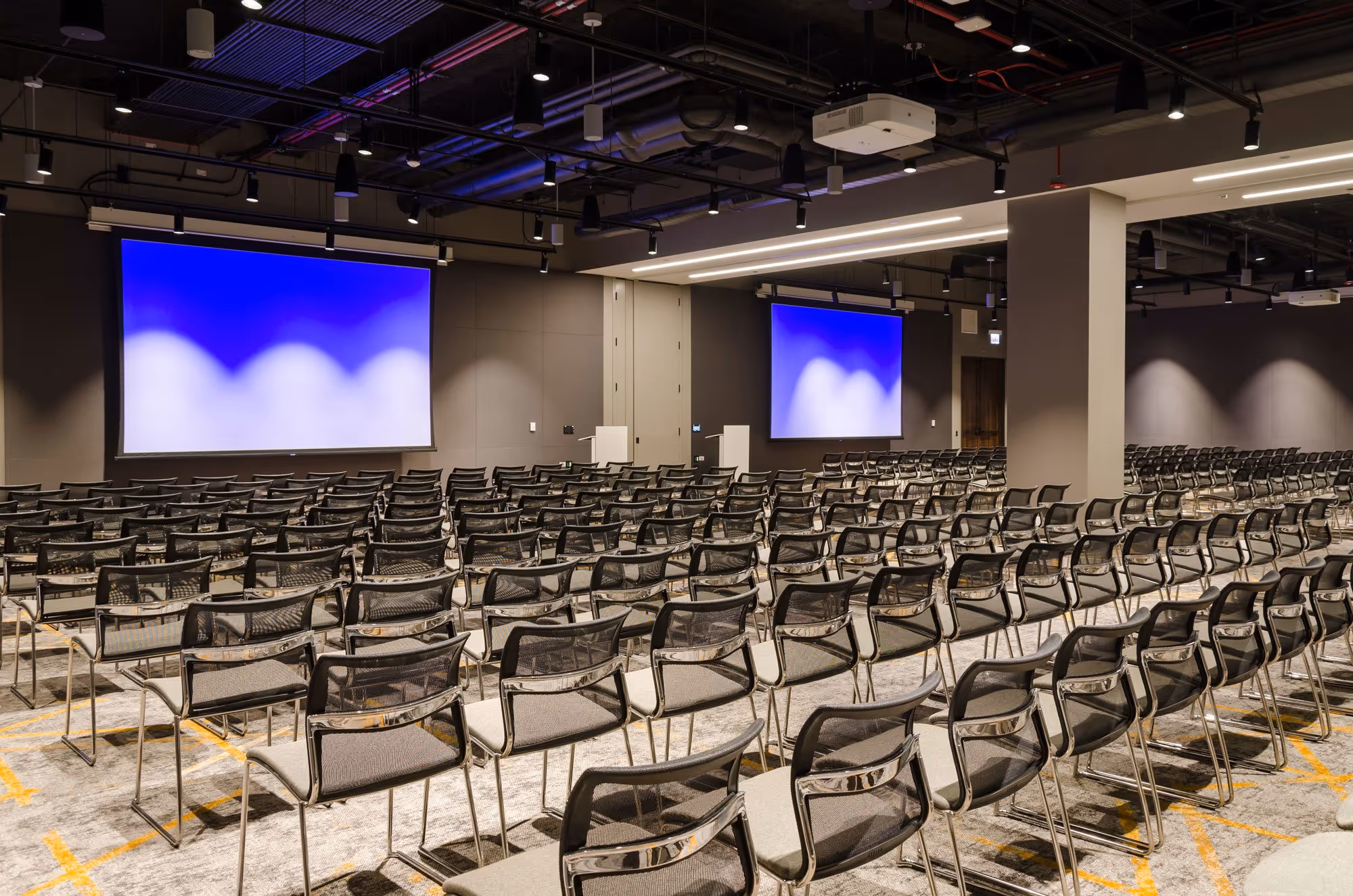 A large room with a blue screen and many chairs.