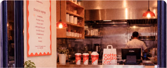 Intérieur du restaurant Cotto avec son identité visuelle appliquée au lieu et aux supports.