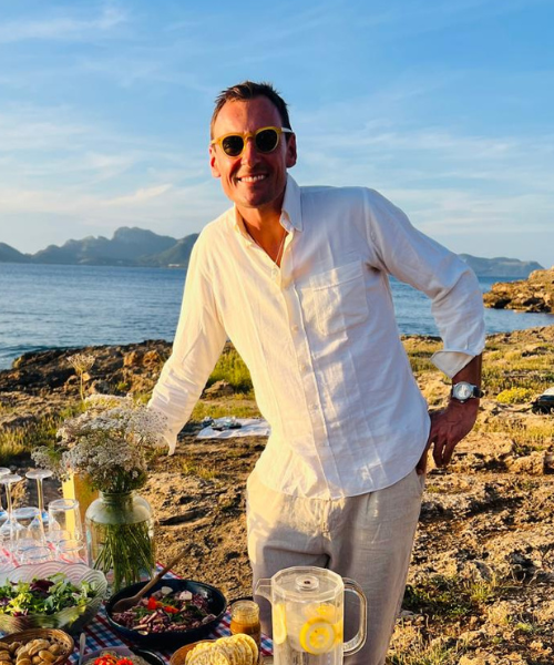 Man standing on the stone shore in whit t-shirt with glasses