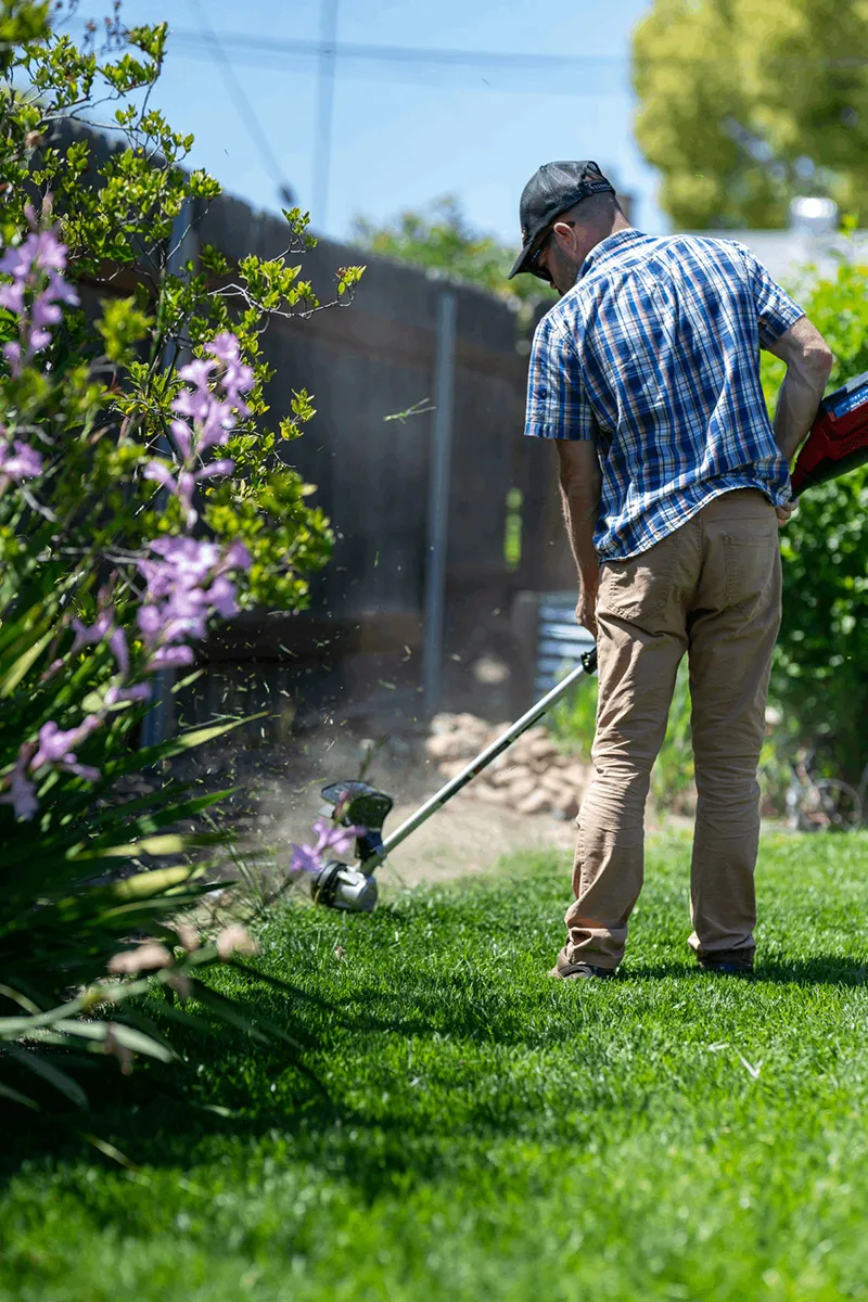 Gärtner bei der Arbeit mit der Motorsense – professionelle Gartenpflege durch Daniel Lasser Gartenbau