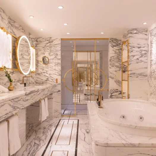 Salle de bain raffinée avec baignoire en marbre et éclairage tamisé à l’Hôtel du Collectionneur.