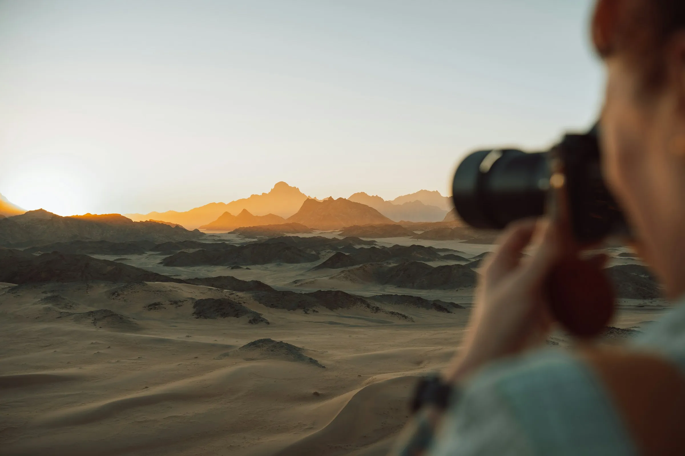 A woman taking a picture of a mountain range.