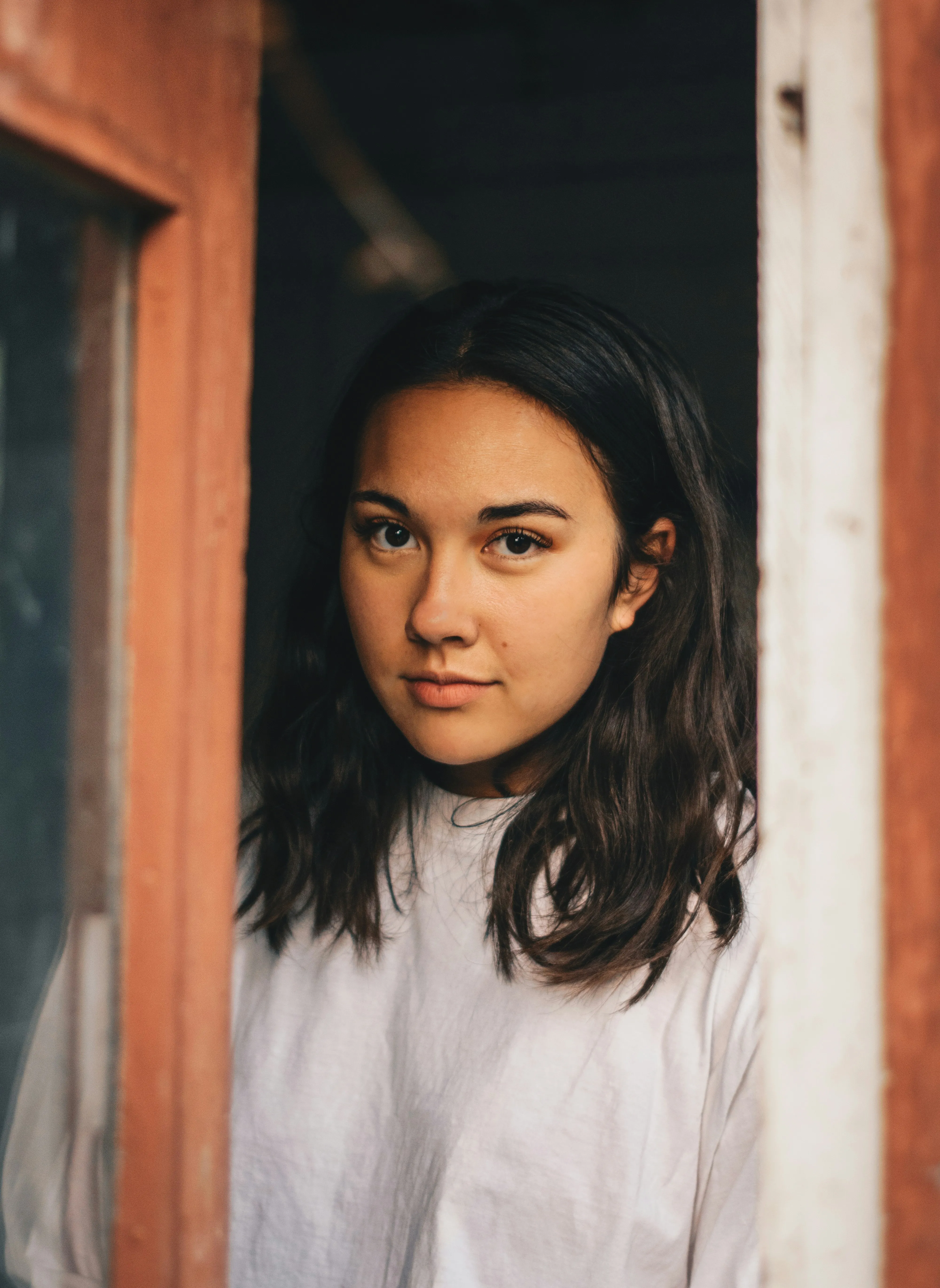 A woman looking out of a window with a serious look on her face.