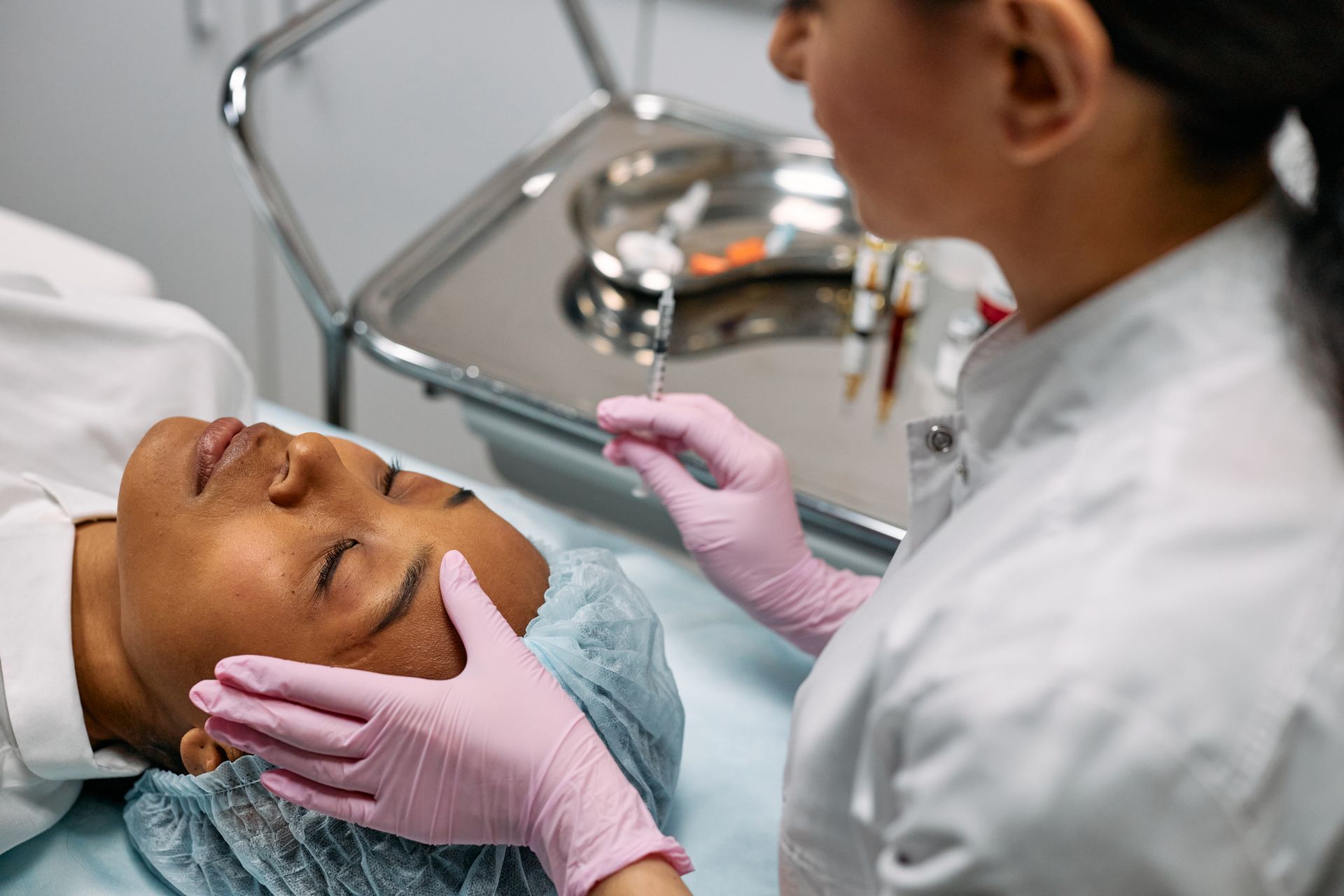 Injection d'acide hyaluronique dans la joue, patiente allongée au cabinet