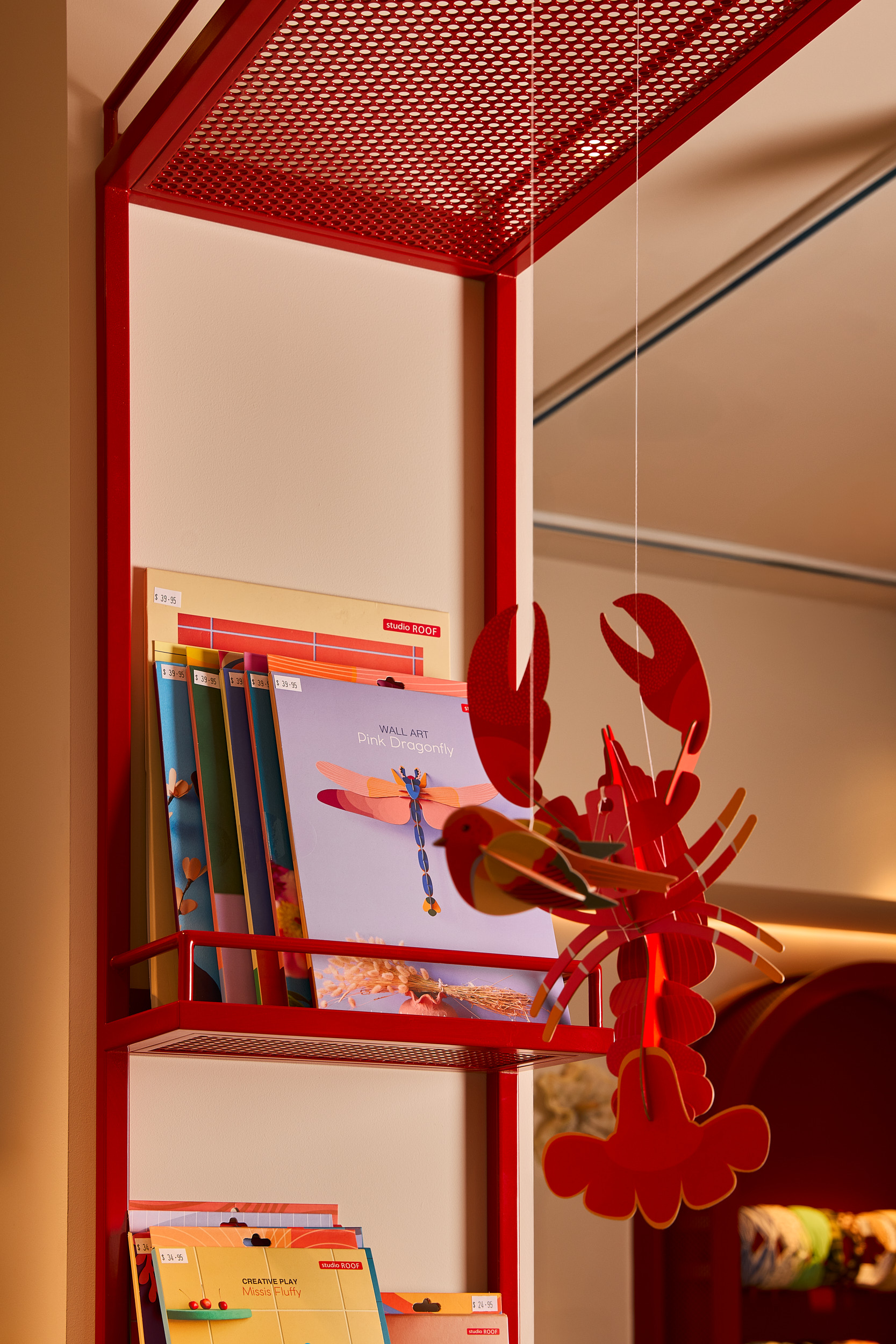 Hanging Lobster Books Red Perforated Open Shelving White Wall Colour in Mooii. Photo by Michael Gazzola, Jake Roden.