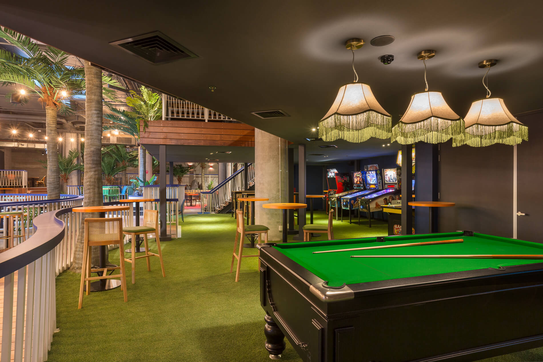 Pool Table Pendant Lights High Chairs Column Palm Trees Green Grass Carpet Special Railing Arcade Machines in Moon Dog Doglands. Photo by Ari Hatzis.