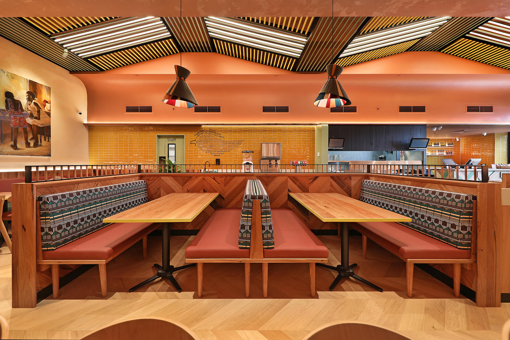 Rust Bench Seating Parquet Wood Base Tribal Pattern Backrest Ochre Wall Tiles Batten Ceiling Funnel Pendants in Nandos. Photo by Michael Gazzola.