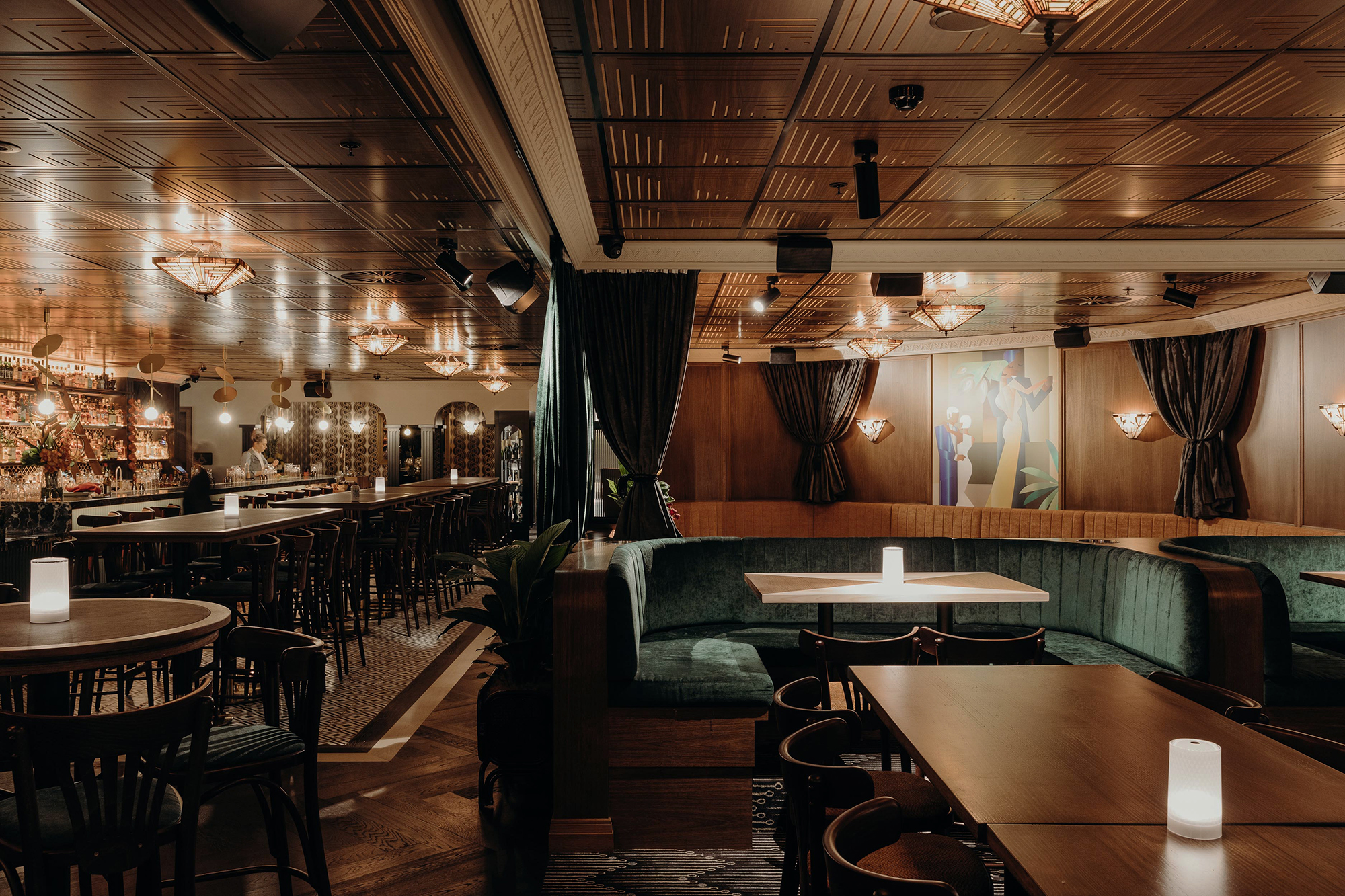 Emerald Velvet Banquettes Oak Tables Decorative Timber Ceiling Fan Wall Lights Green Velvet Curtains Mural Artwork in Nick & Nora’s. Photo by Ryan Sauer.