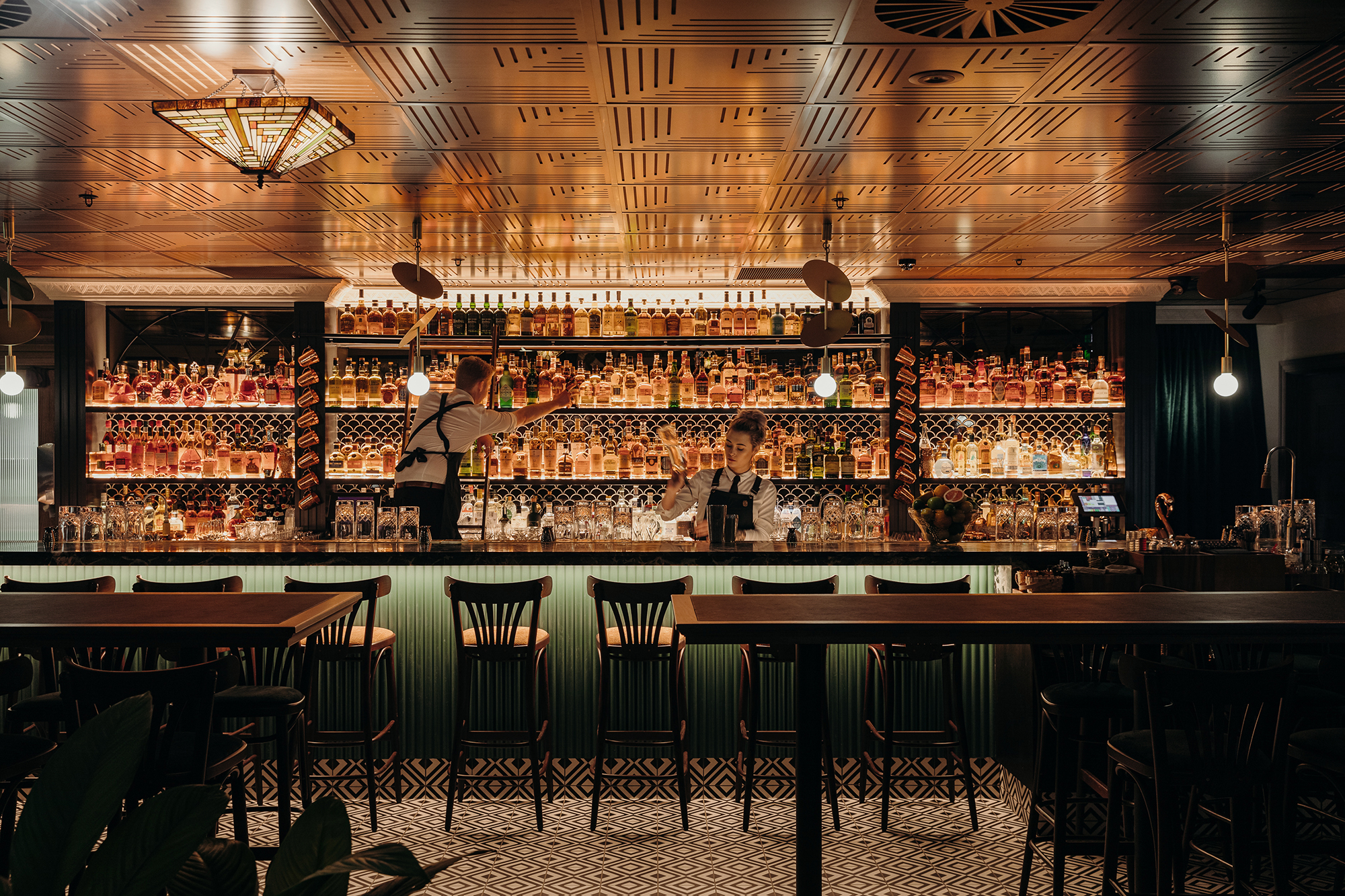Backlit Spirits Shelving Green Fluted Bar Front Scalloped Tile Detail Art Deco Ceiling Mosaic Floor Tiles in Nick & Nora’s. Photo by Ryan Sauer.