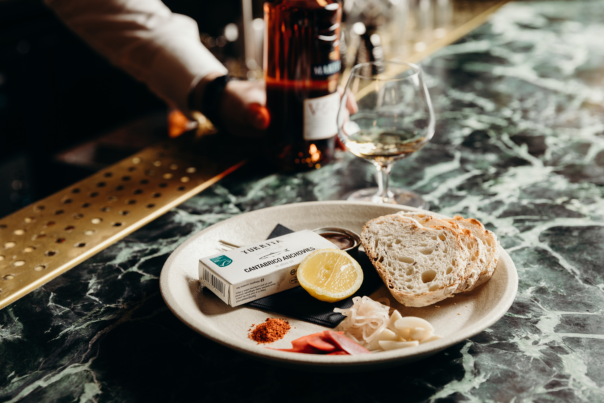 Verde Green Marble Countertop Perforated Brass Drip Tray Artisanal Entree Plate Crystal Glassware Detail in Nick & Nora’s. Photo by Ryan Sauer.
