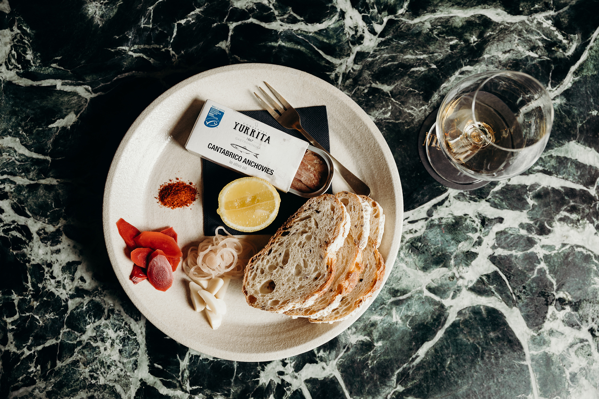 Gourmet Plating Sourdough Bread Cantabrico Anchovies Green Marble Tabletop Wine Glass Detail Overhead View in Nick & Nora’s. Photo by Ryan Sauer.