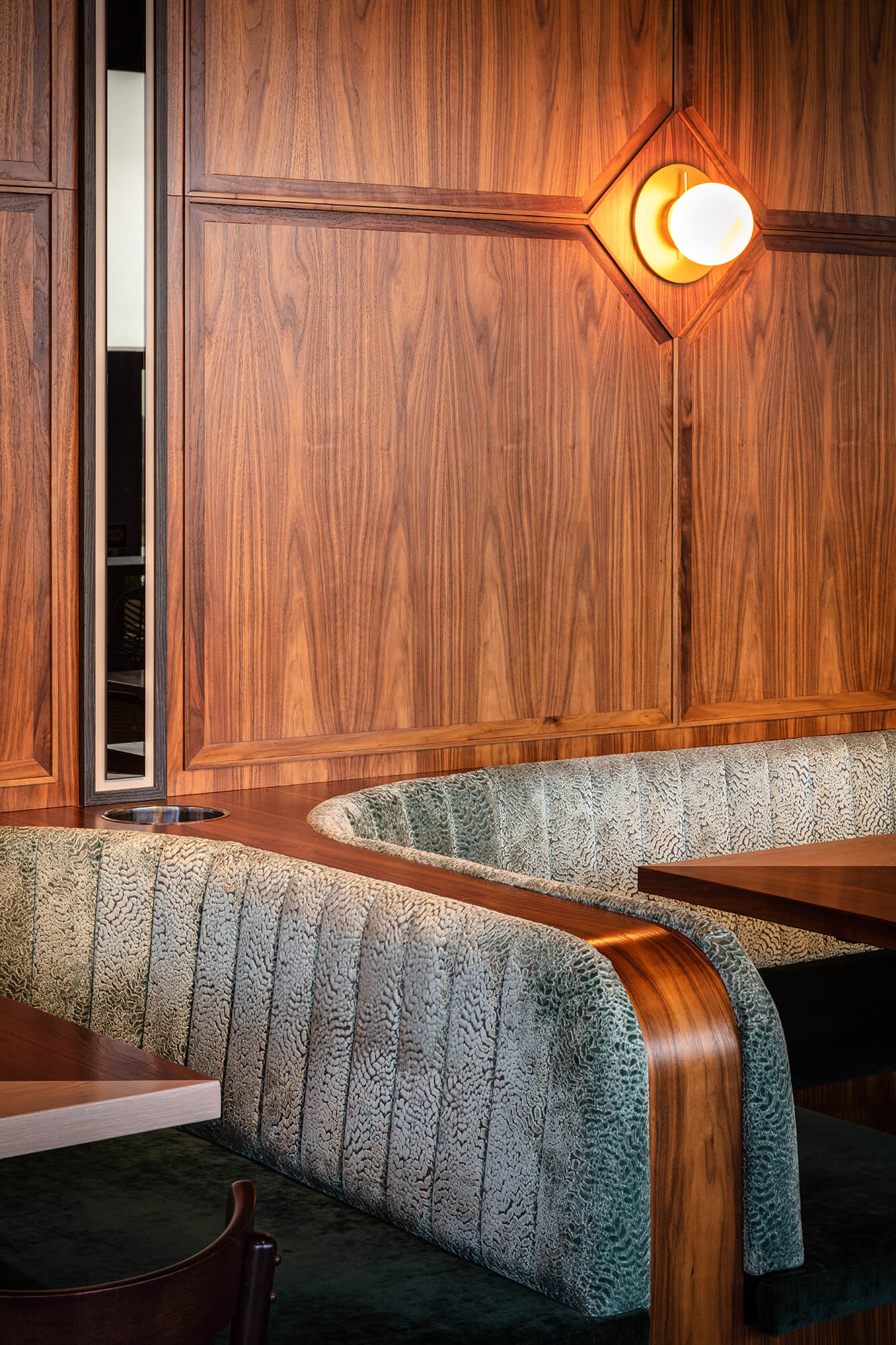 Sage Animal-Print Banquette Curved Timber Armrest Walnut Panelling Inset Brass Globe Sconce Diamond Joinery Detail in Nick & Nora’s. Photo by Ryan Sauer.