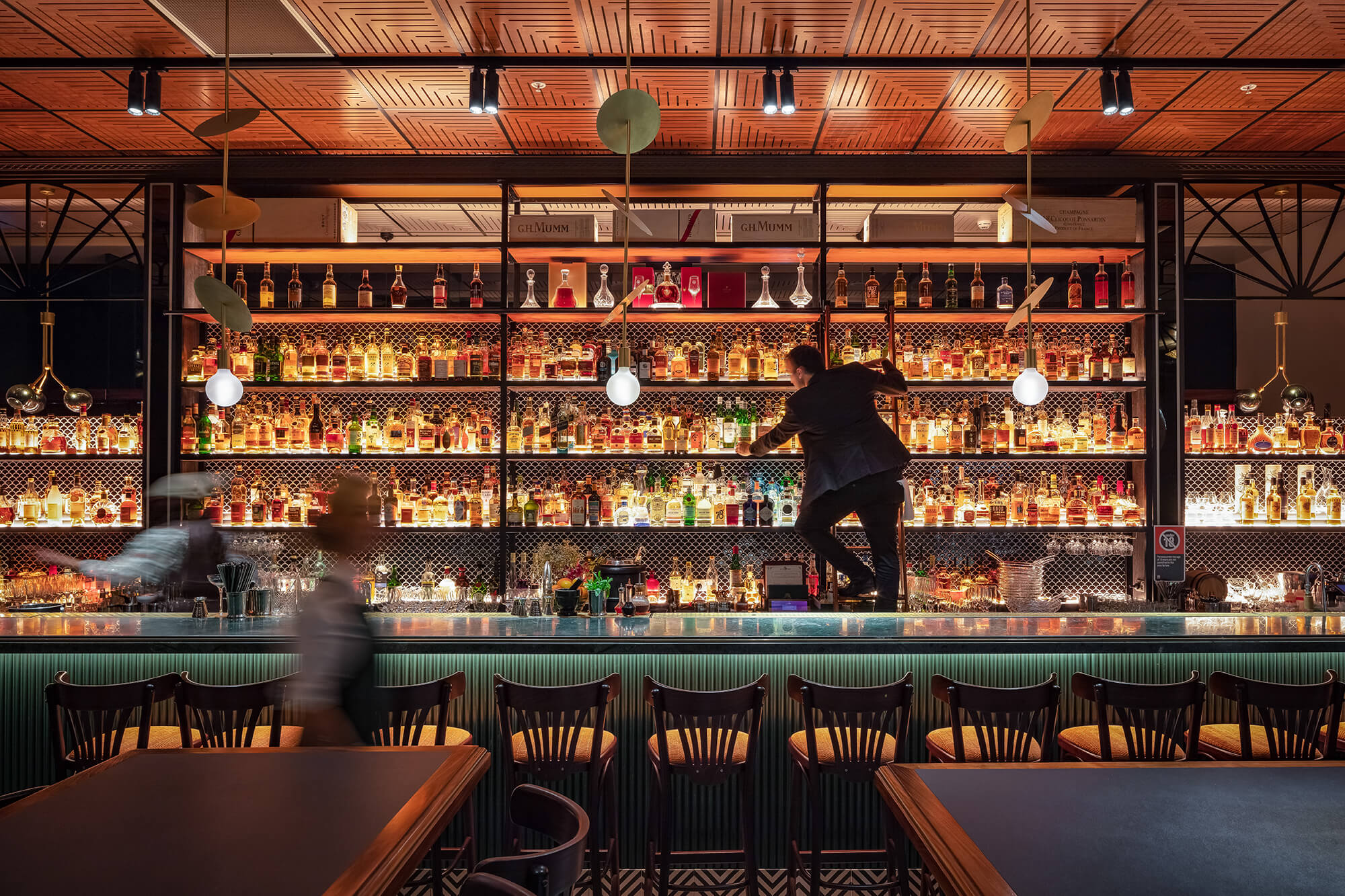 Backlit Spirits Gallery Teal Fluted Bar Counter Gold Disc Pendants Timber Parquet Ceiling Mosaic Tiled Floor in Nick & Nora’s. Photo by Ryan Sauer.