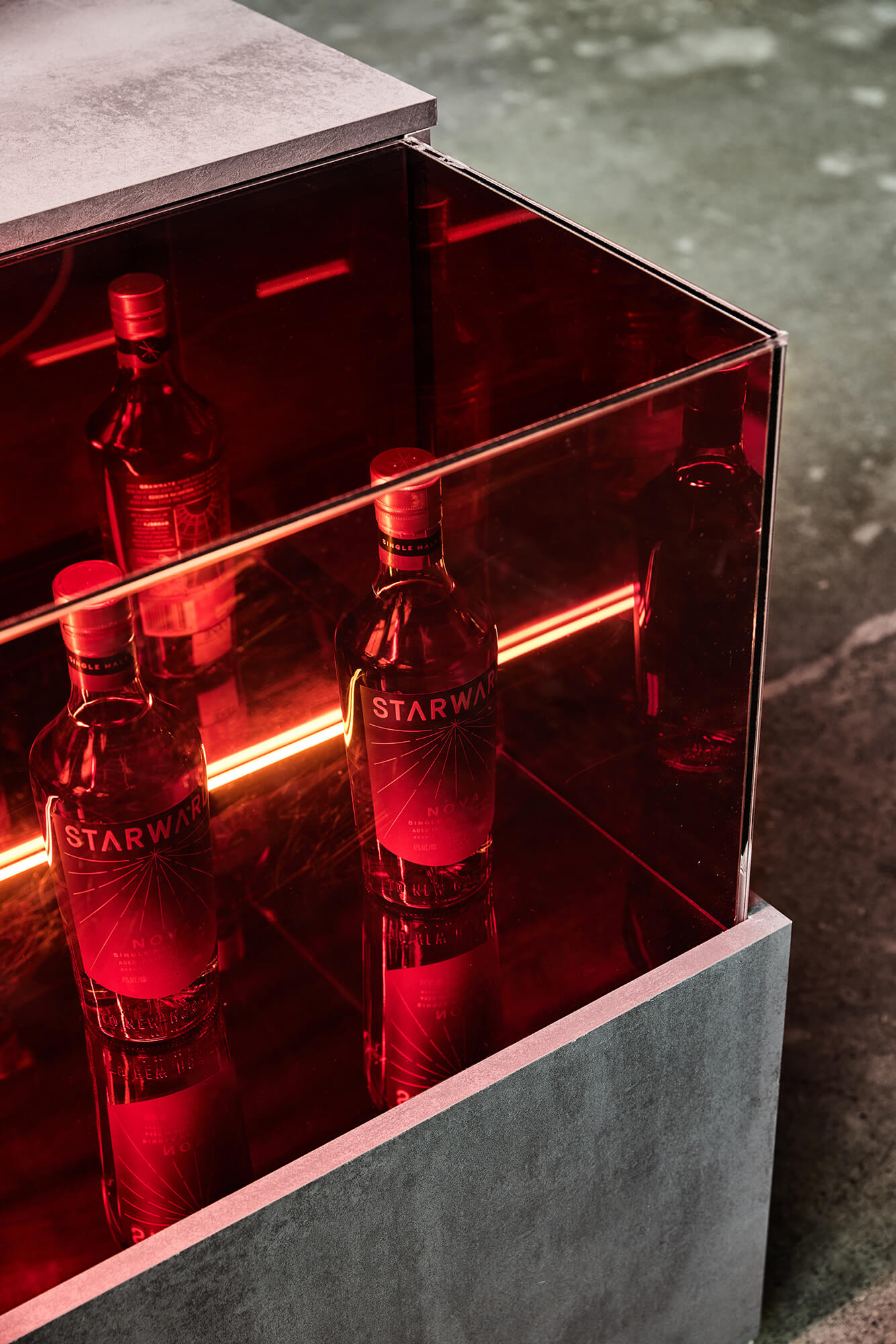 Crimson Tinted Glass Showcase Interior Illumination Concrete-Look Plinth Mirror Reflections Premium Whisky Bottle Curation in Starward. Photo by James Geer.