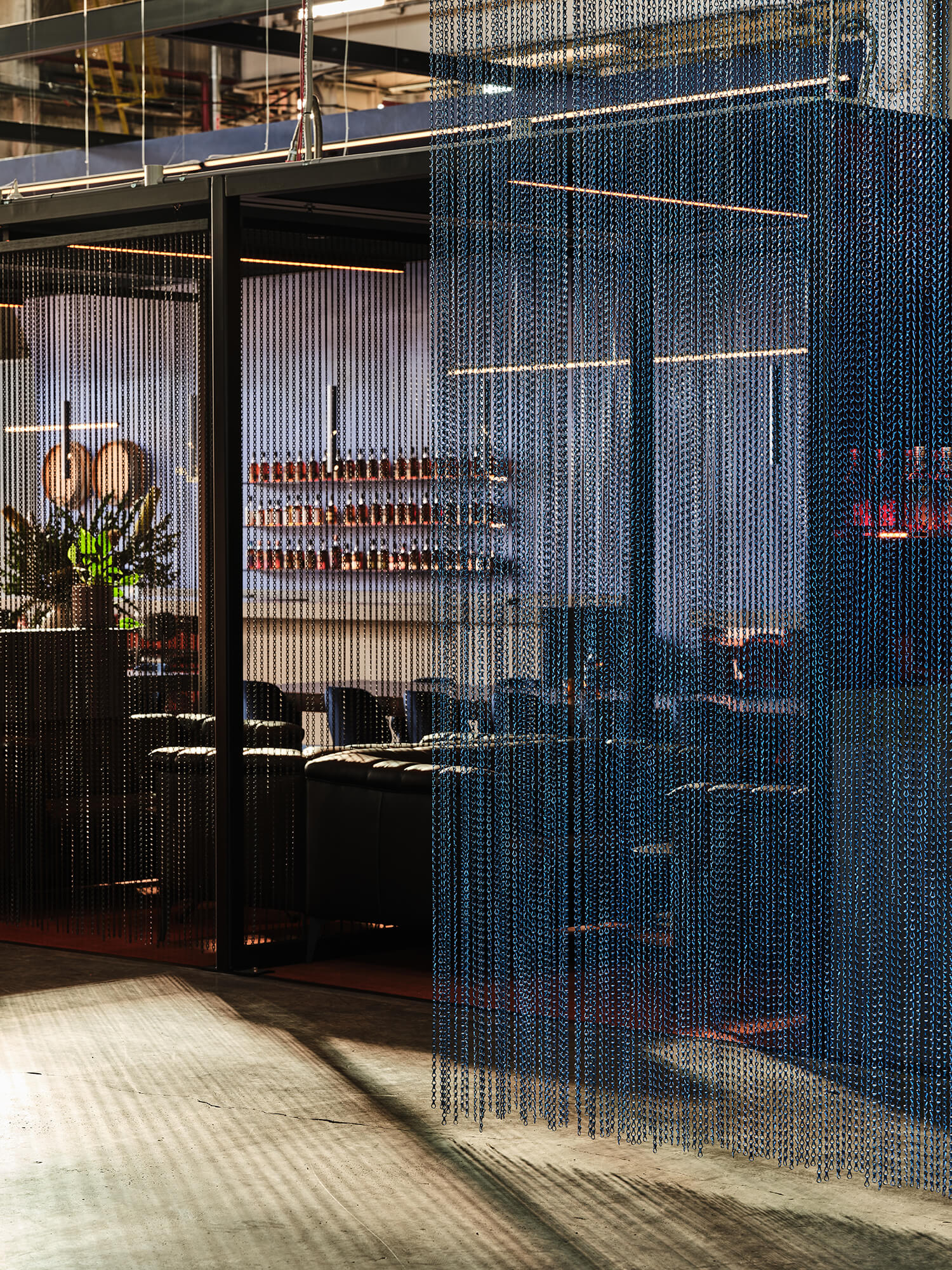 Blue Chainmail Screen Divider Leather Lounge Seating Black Steel Framework Polished Concrete Floor Industrial Distillery Aesthetics in Starward. Photo by James Geer.