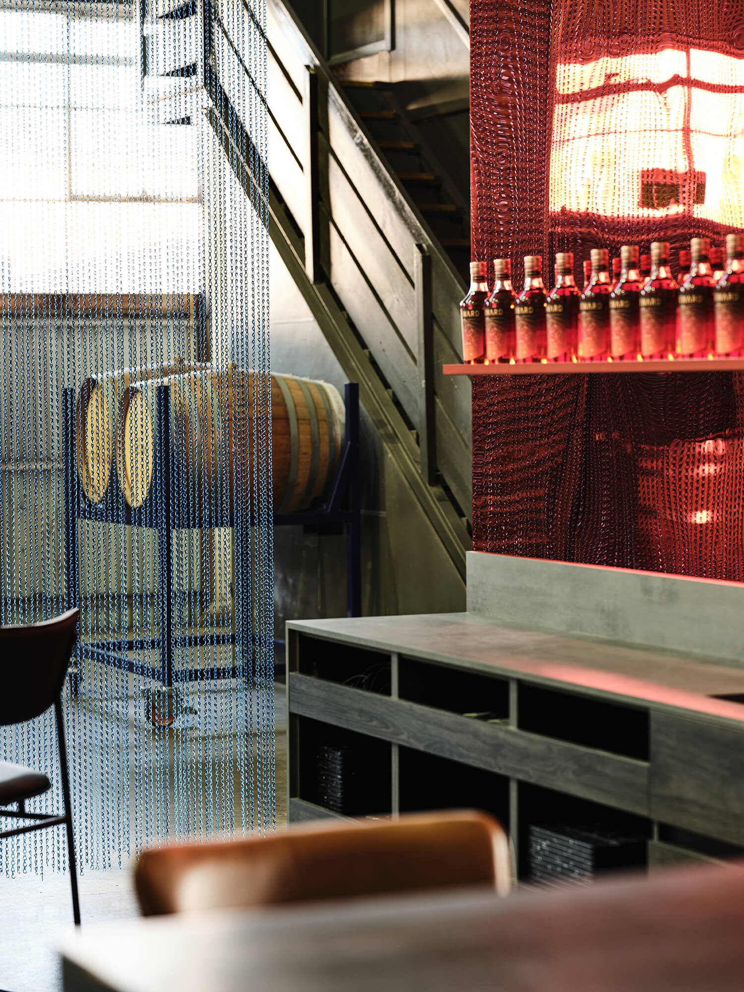 Crimson Ripple-Glass Backdrop Timber Barrel Rack Chainmail Screening Concrete Joinery Industrial Staircase Detail Raw Distillery Mood in Starward. Photo by James Geer.