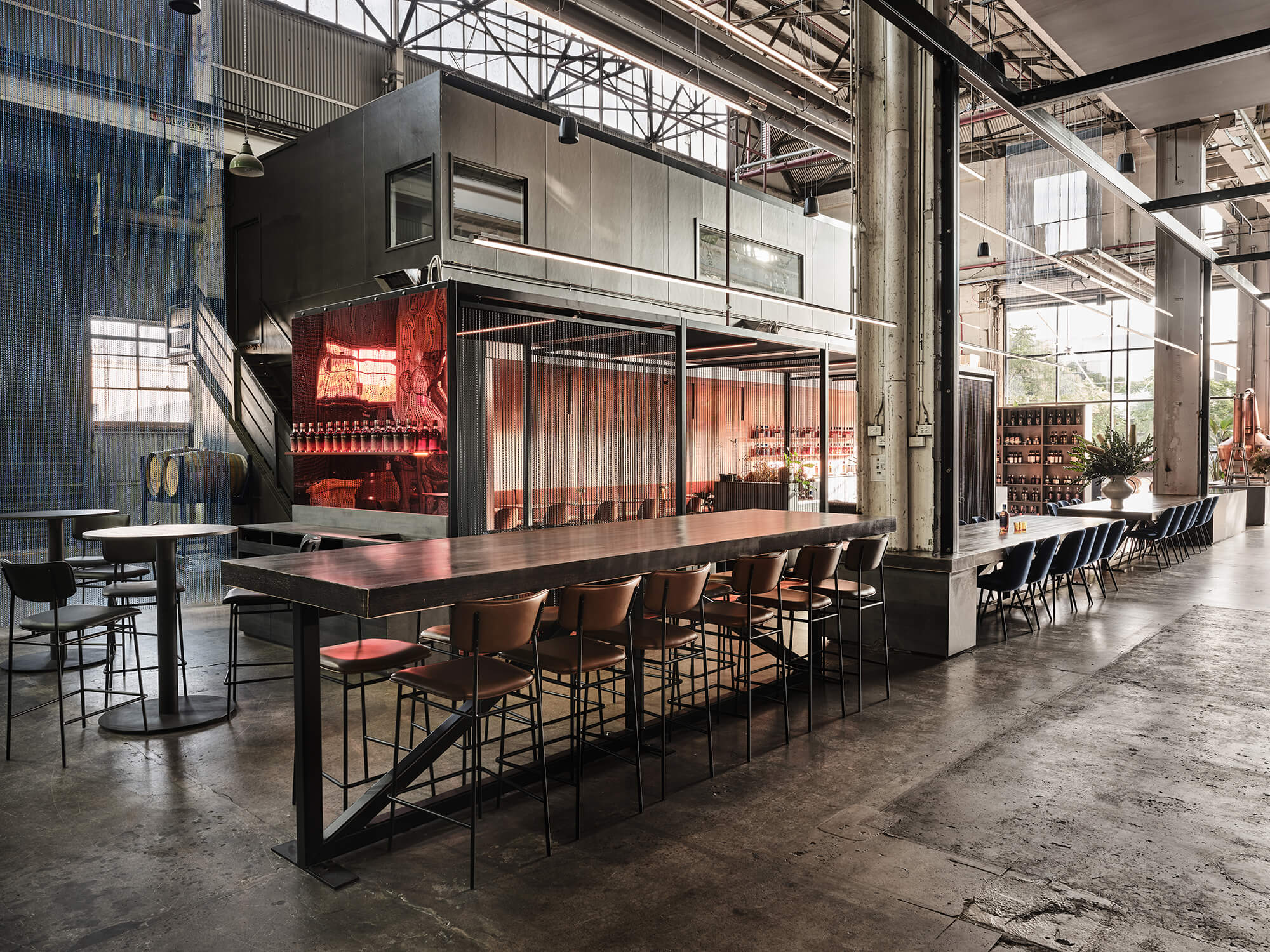 Large Timber Communal Tables Tan Leather Bar Stools Industrial Sawtooth Roof Exposed Concrete Pylons Architectural Distillery Volume in Starward. Photo by James Geer.