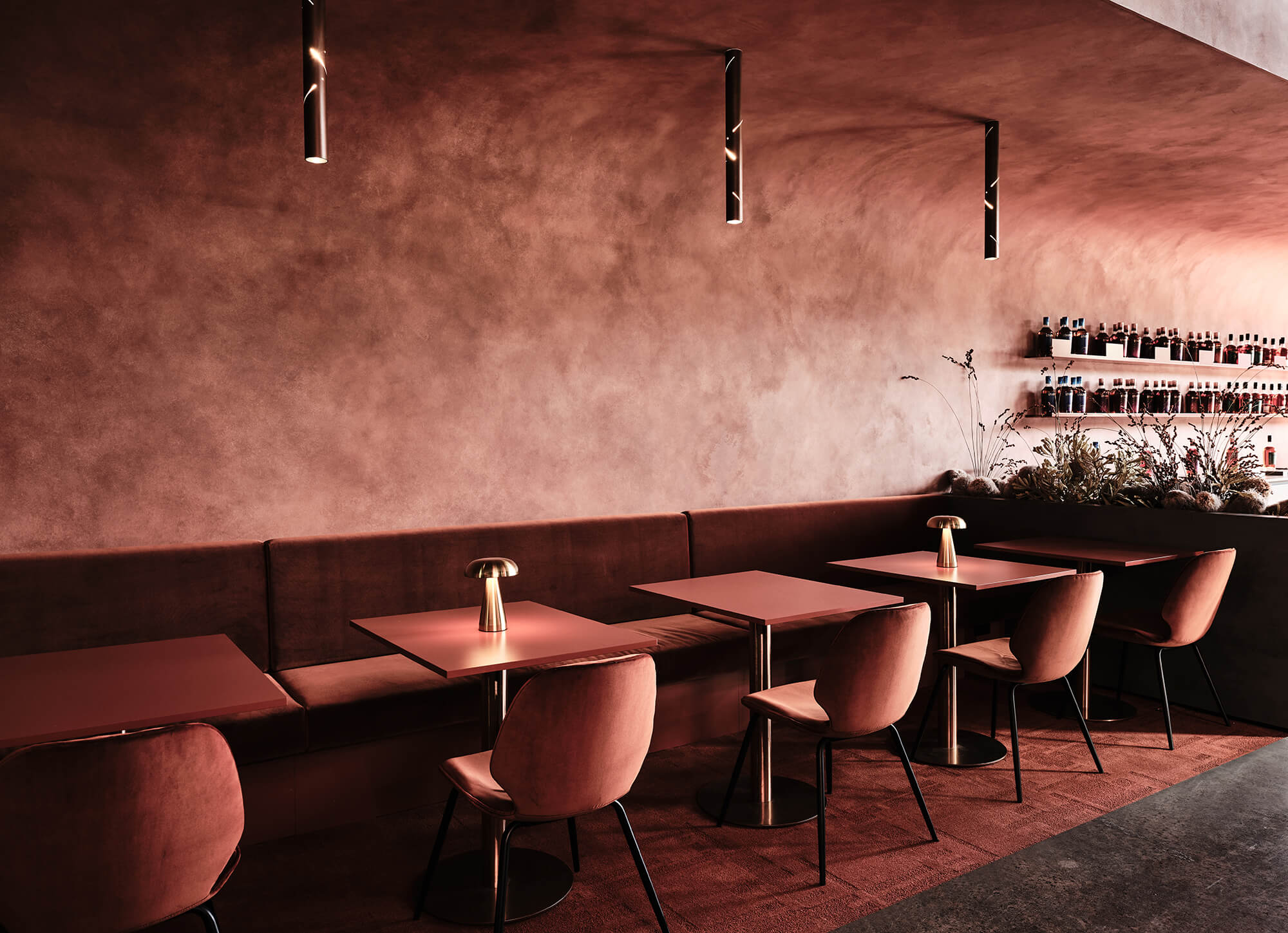 Monochromatic Clay-Toned Dining Niche Velvet Banquette Seating Warm Dome Lighting Arched Plaster Ceiling Perforated Pipe Pendants in Starward. Photo by James Geer.