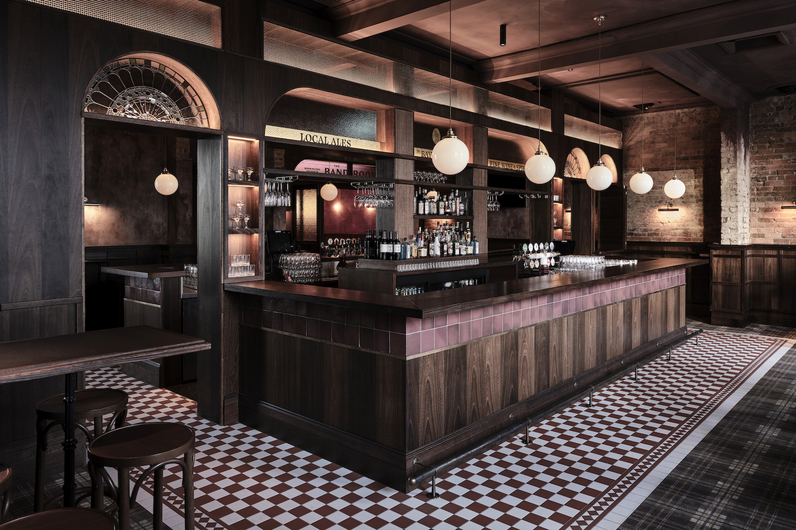 Classic Timber Bar with Checkerboard Tiling Spherical Opal Pendants Stained Glass Archways Heritage Wood Paneling Vintage Pub Interior in The Bay Hotel. Photo by James Geer.