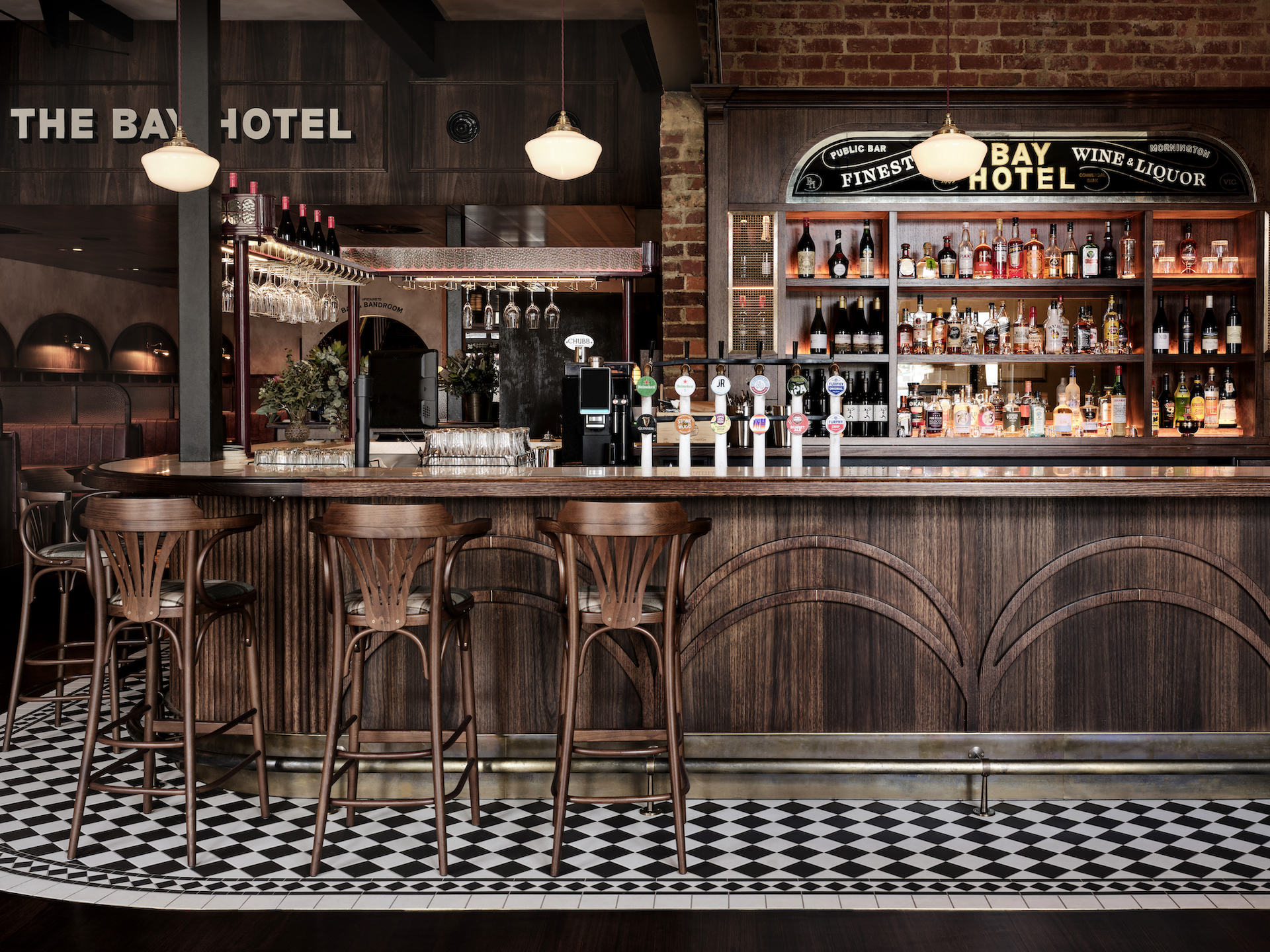 Symmetry in Heritage Design Frontal Timber Bar Gold Leaf Mirror Signage Illuminated Spirits Display Bentwood Stools Checkerboard Tiles in The Bay Hotel. Photo by James Geer.