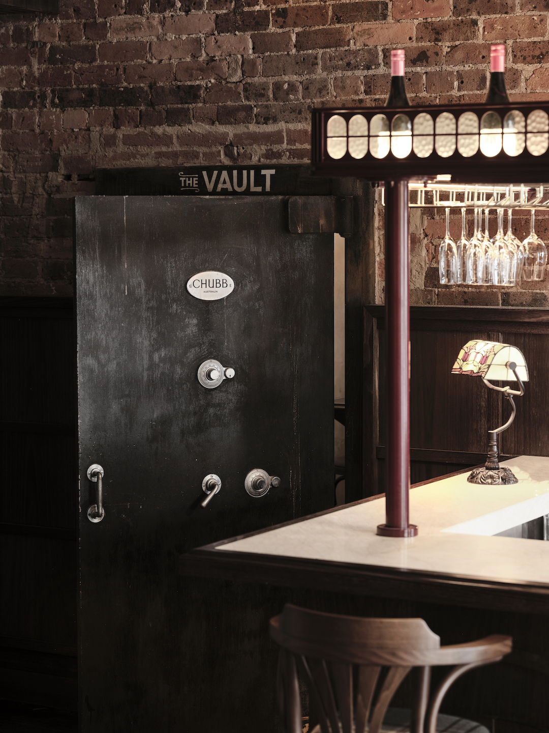 Chubb Heavy Steel Safe Door Entryway Exposed Red Brick Walls Marble Countertop Ornate Glass Pendant Lights Heritage Pub Charm in The Bay Hotel. Photo by James Geer.